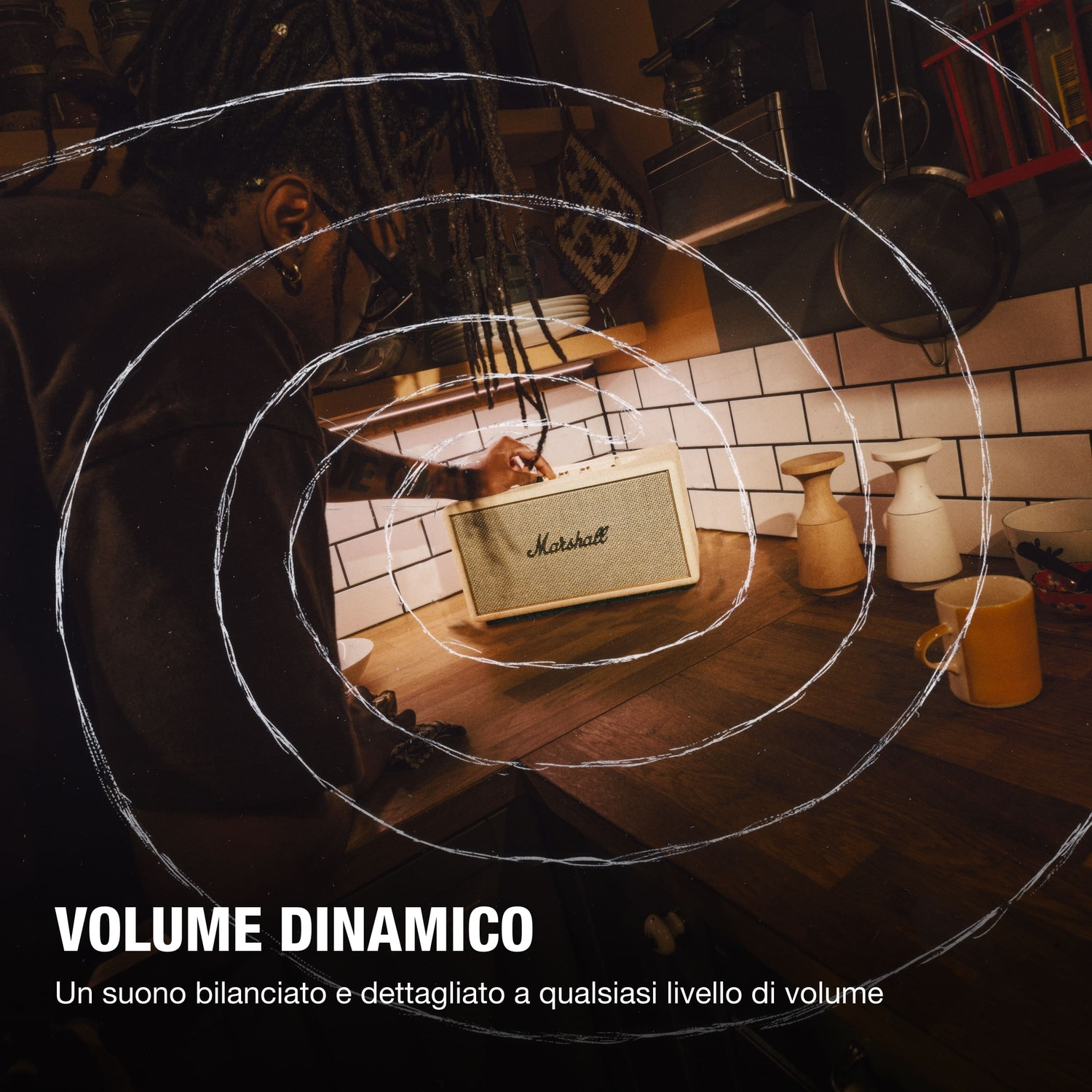 Una persona con dreadlocks usa uno speaker Marshall in cucina.