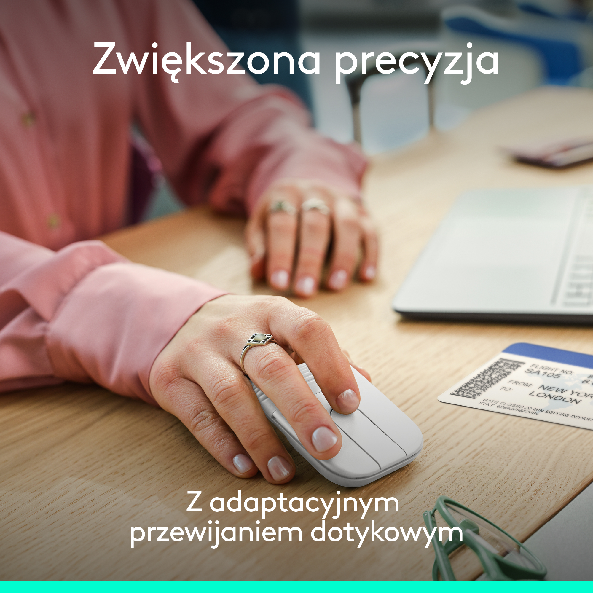 Dłoń osoby używa białej myszy komputerowej na drewnianym biurku, z widocznym biletem lotniczym i laptopem.