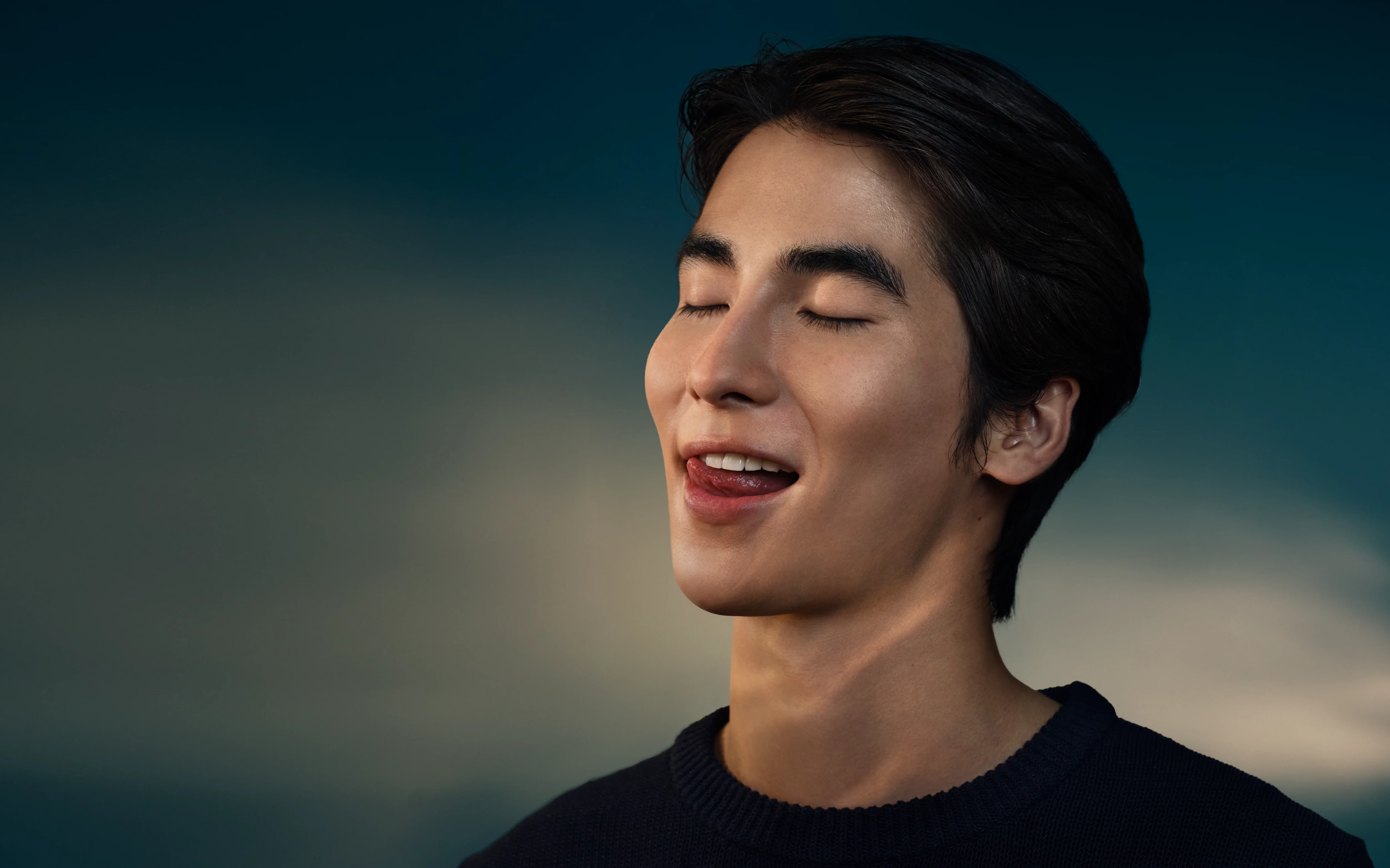 Un jeune homme les yeux fermés, tirant la langue.