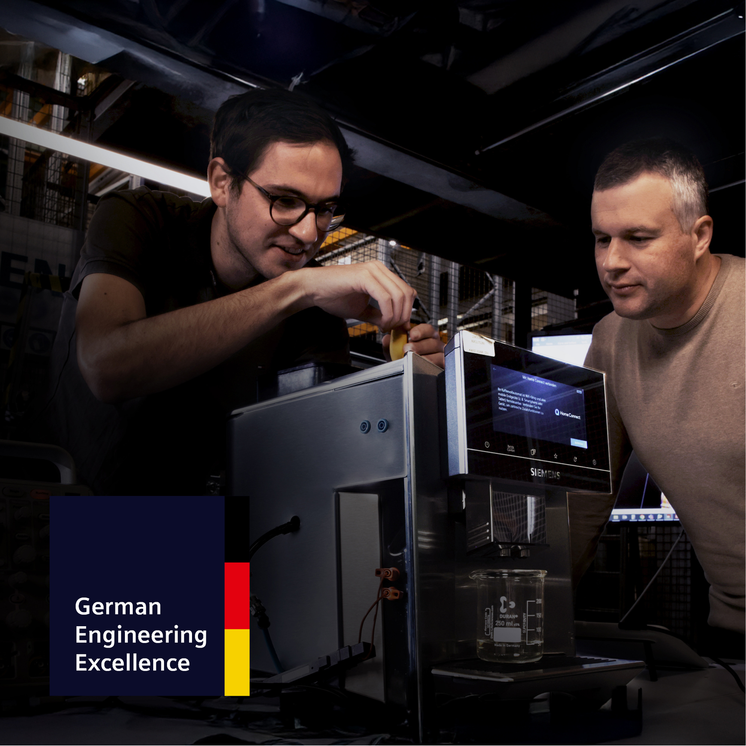 Deux hommes travaillent sur une machine à café Siemens. Un homme avec des lunettes y met quelque chose.
