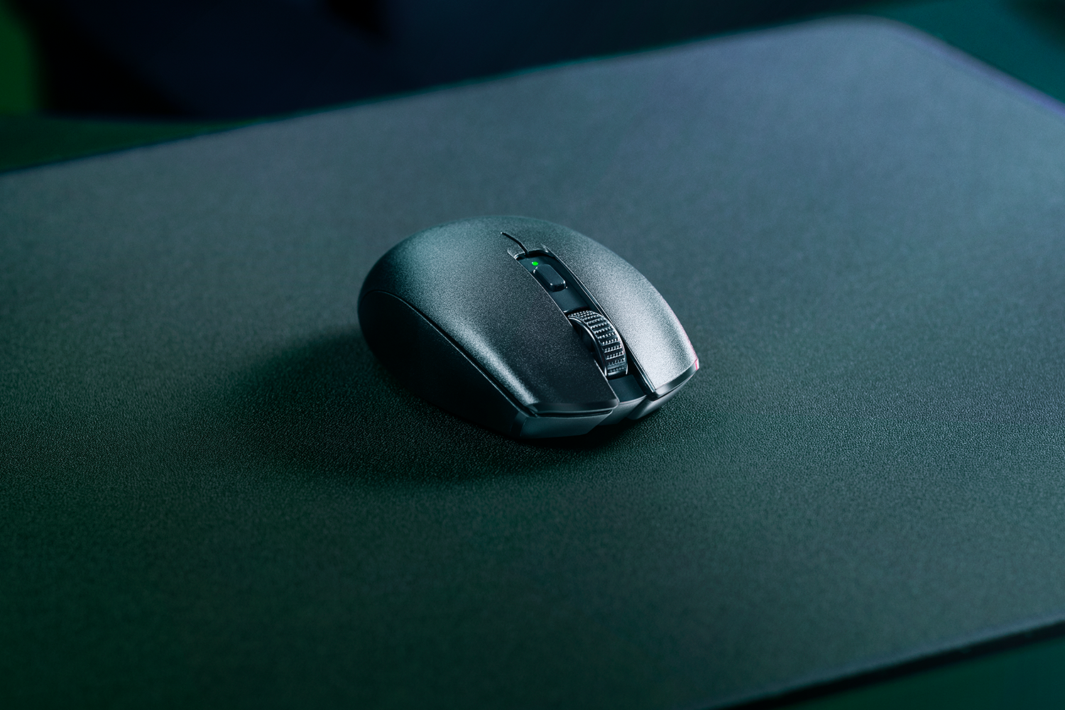 Eine graue Computermouse mit Scrollrad liegt auf einer schwarzen Unterlage.