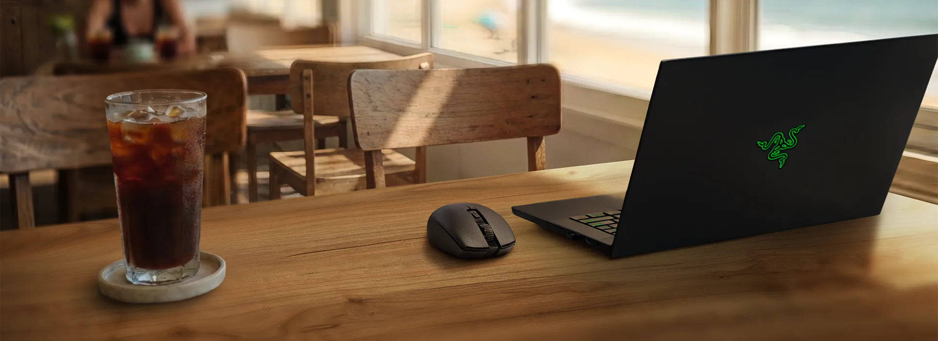 Schwarzer Laptop mit grüner Schlange und Maus neben einem Glas Eistee.