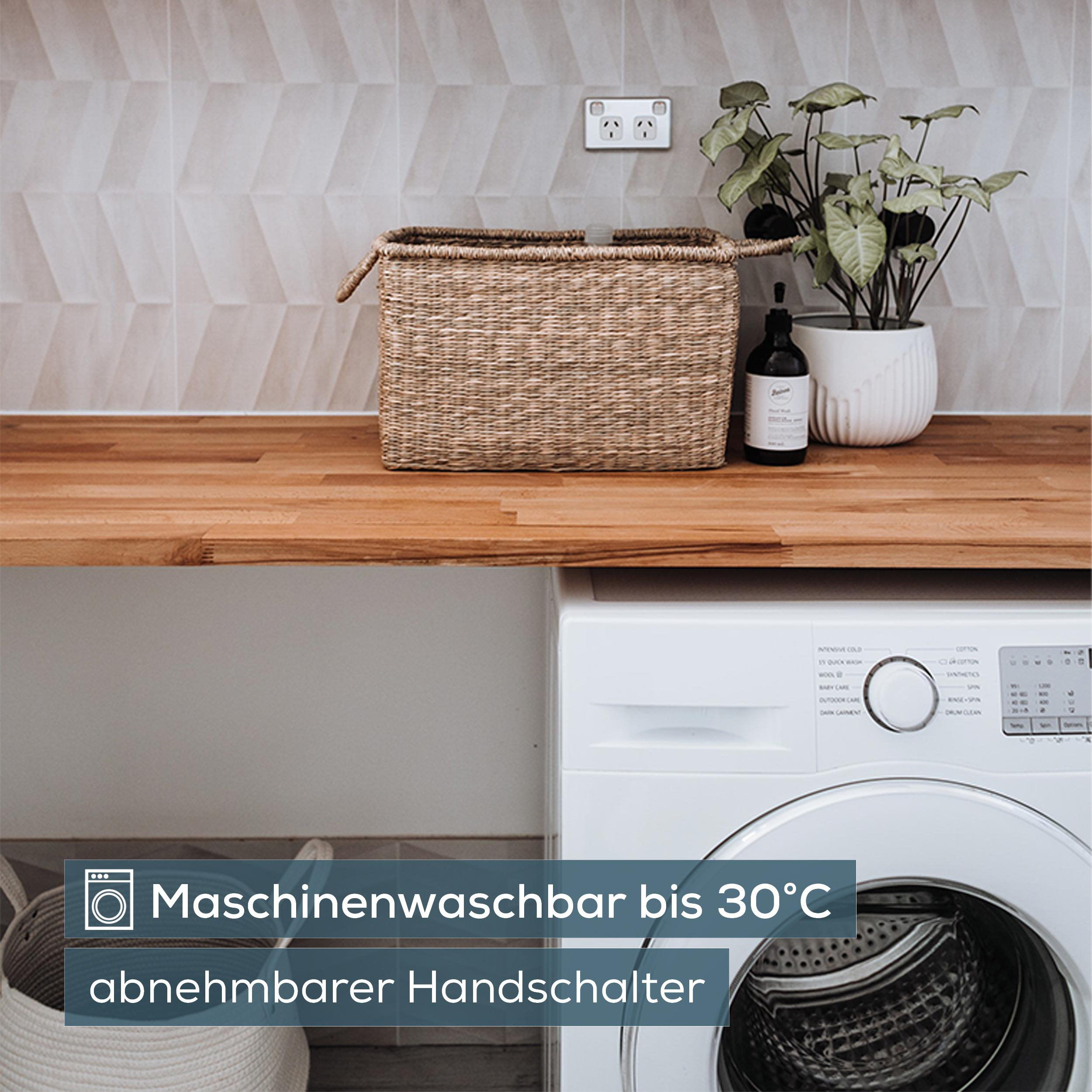 Waschmaschine mit Wäschekorb, Pflanze und Seifenspender auf Holzarbeitsplatte.