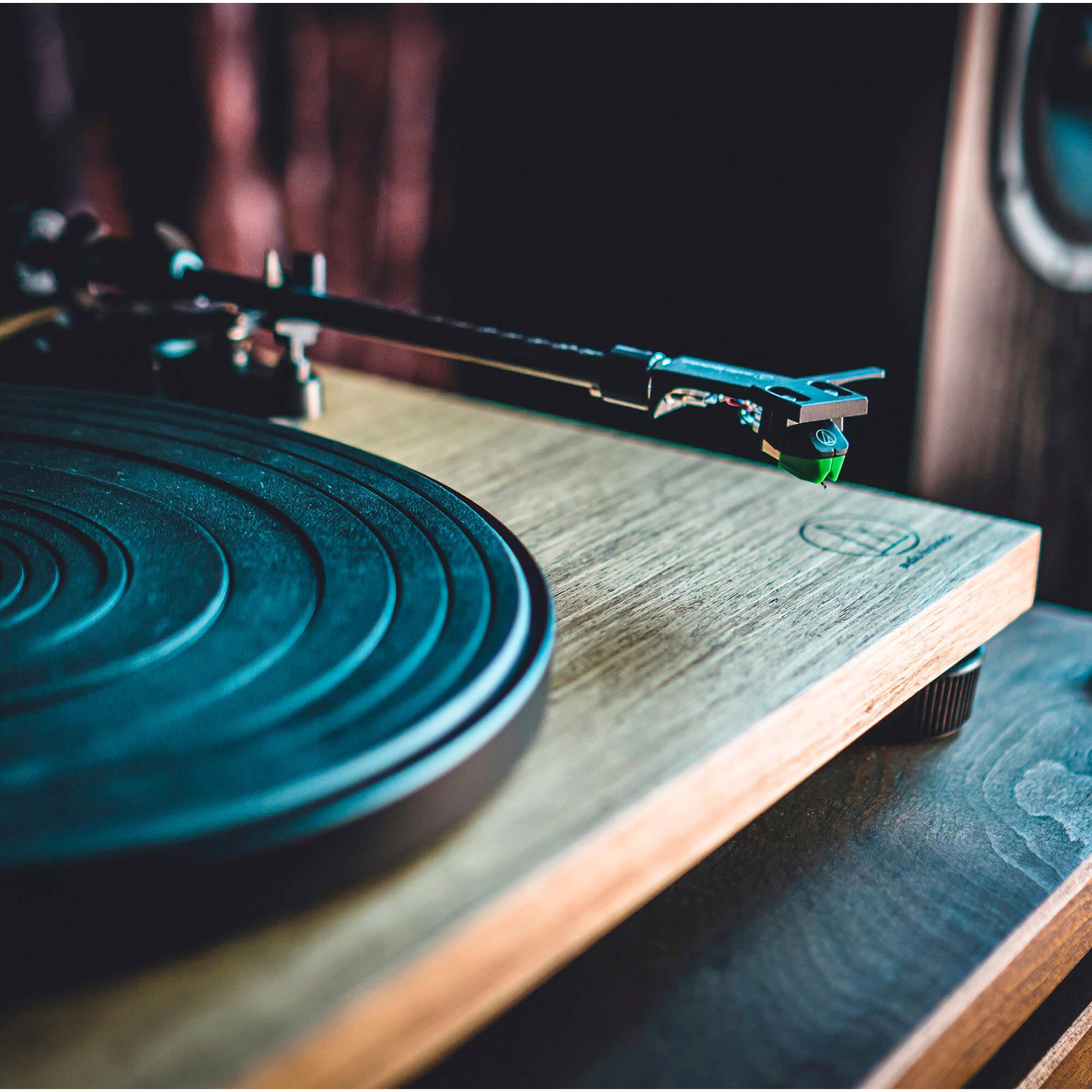 Primo piano di un giradischi con disco in vinile nero e braccio con puntina verde.