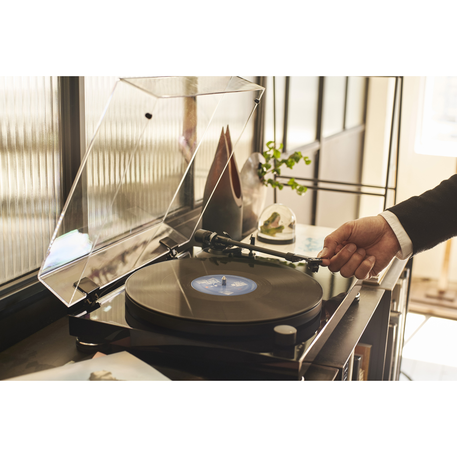 La mano di un uomo posa un disco su un giradischi.