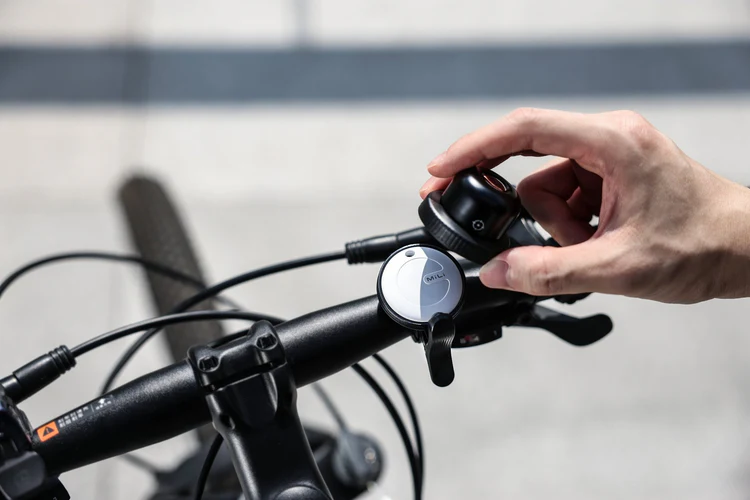 Ręka reguluje dzwonek rowerowy zamontowany na kierownicy.