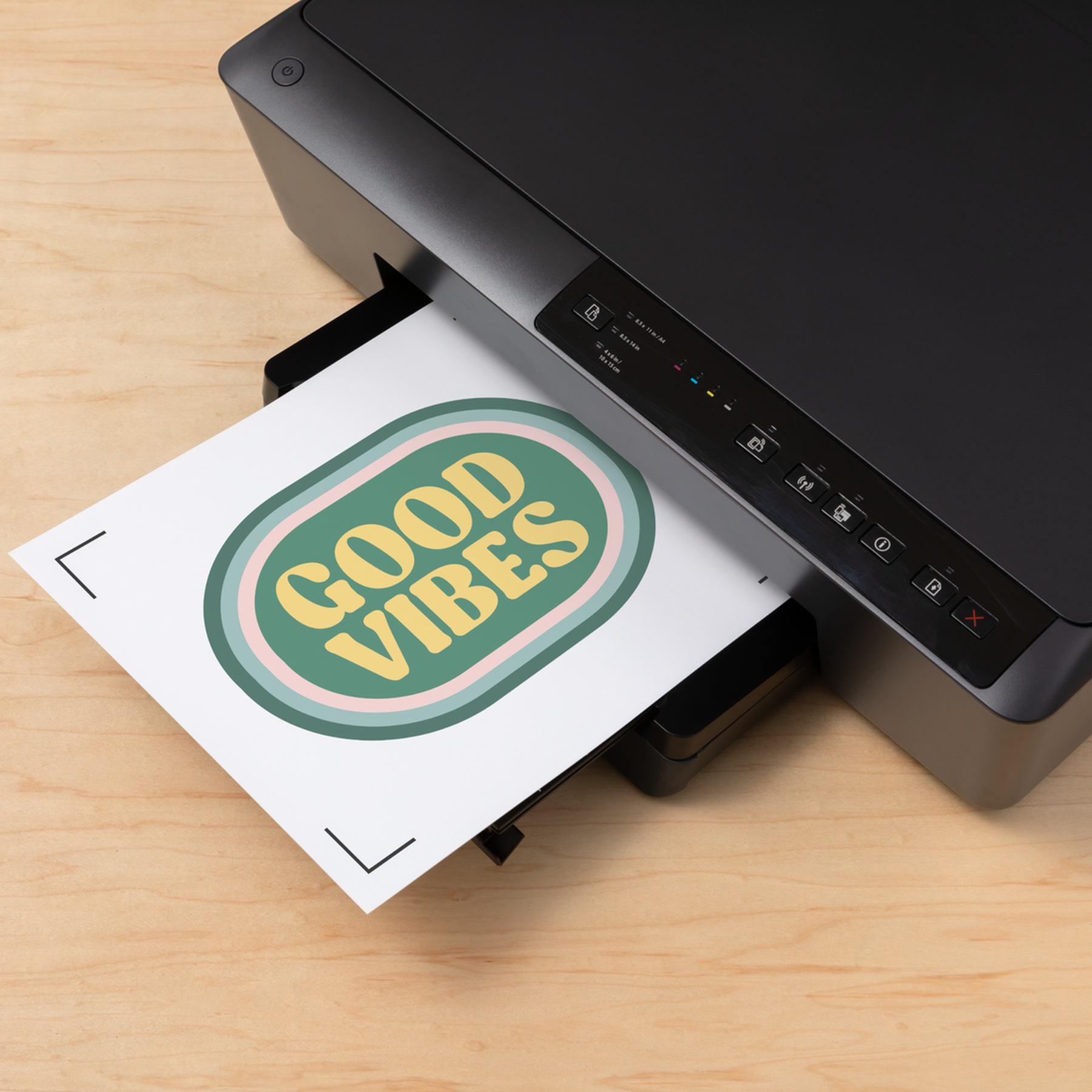Ahşap yüzeyde "GOOD VIBES" yazılı bir kağıt basan siyah yazıcı.