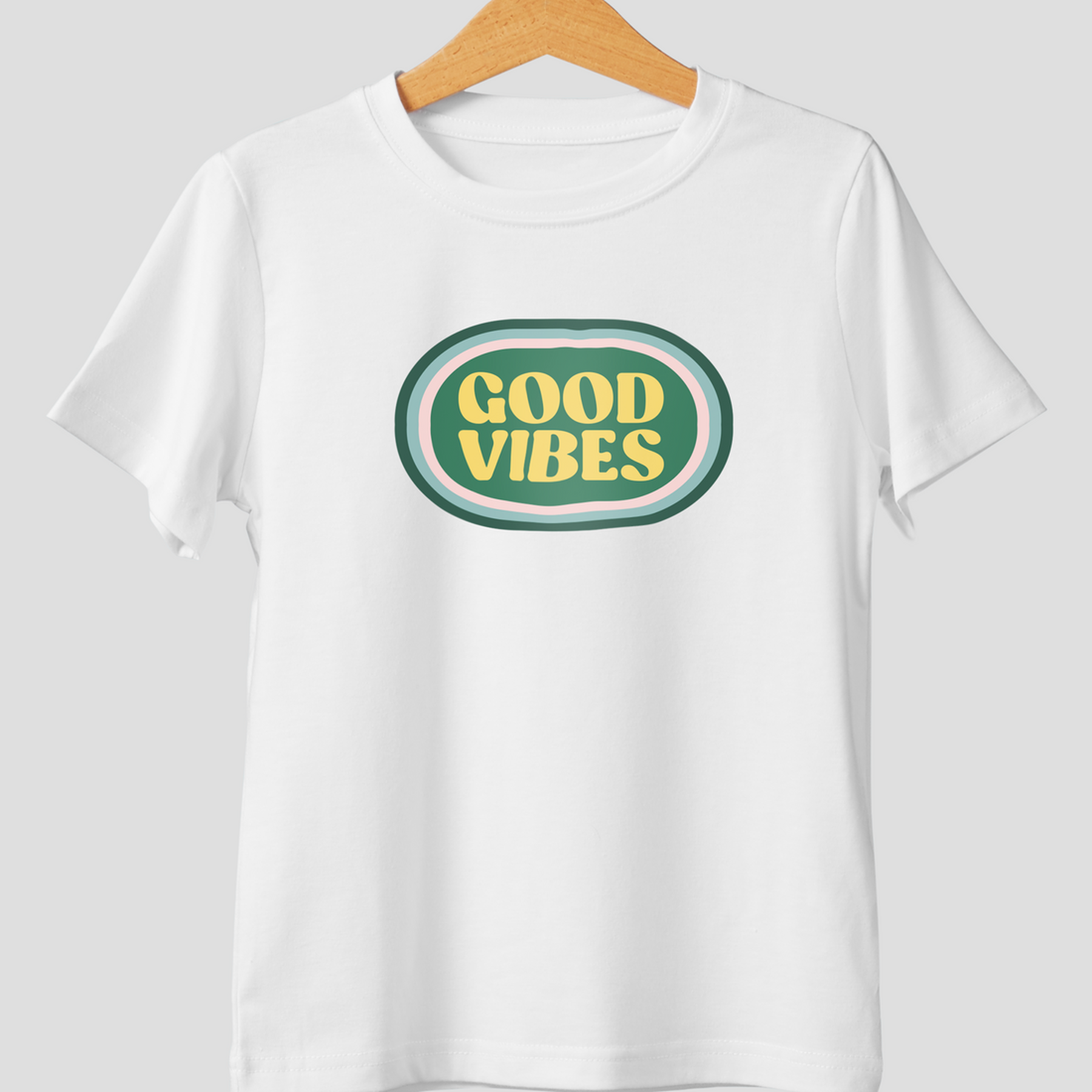 Yeşil oval üzerinde sarı "Good Vibes" yazılı beyaz tişört.