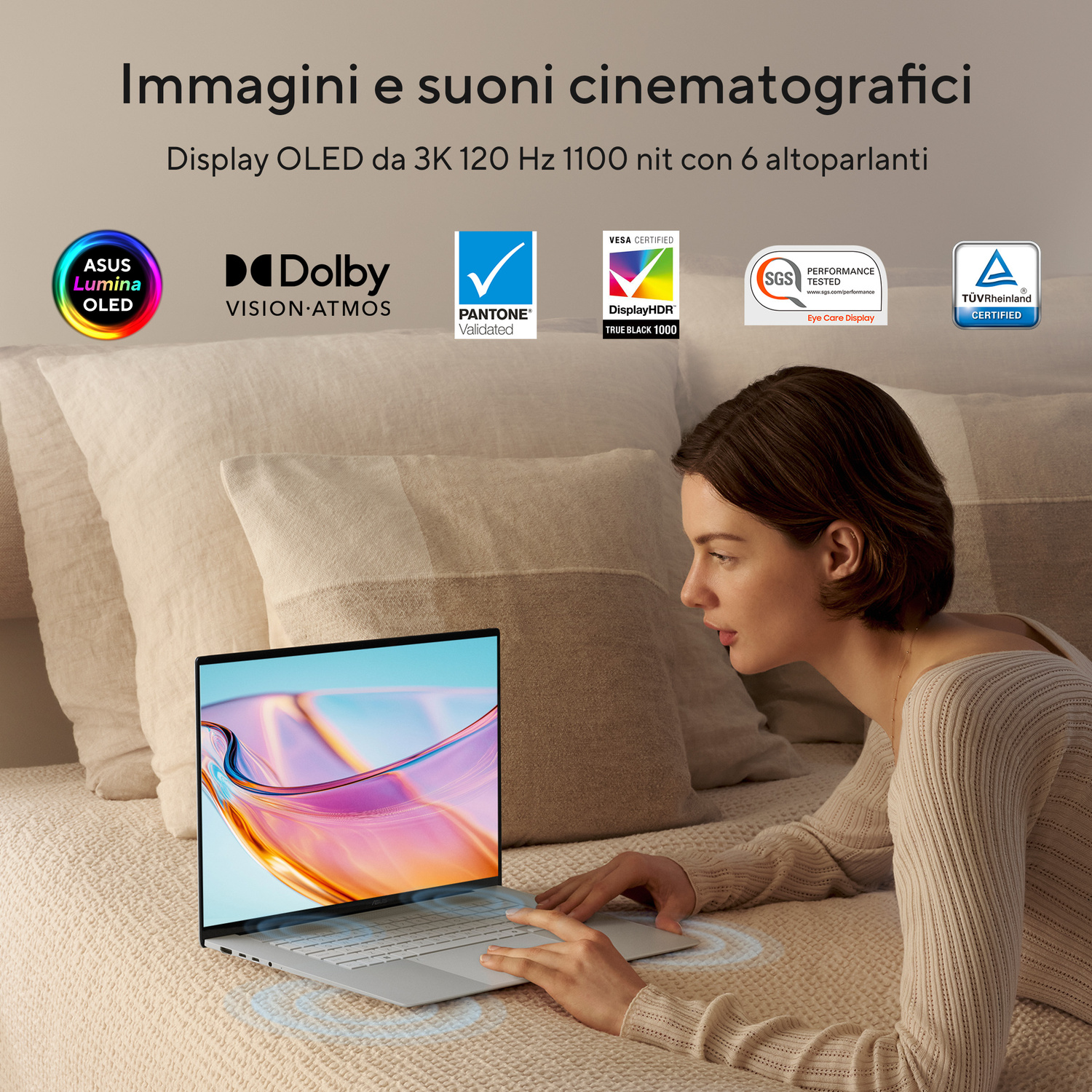 Una donna è sdraiata su un letto usando un laptop con display vibrante. Loghi visibili.