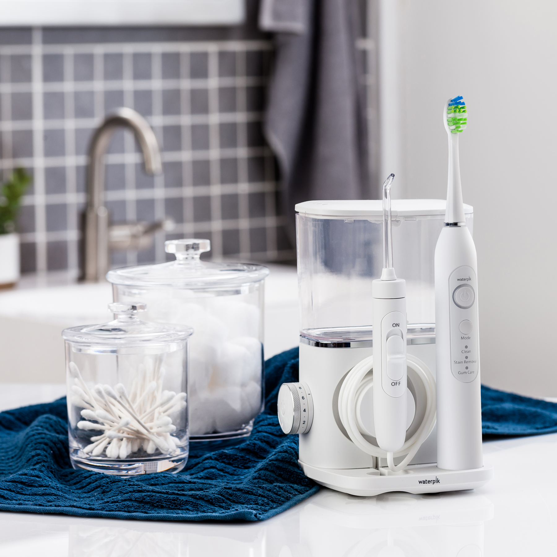 Irygator wodny Waterpik i szczoteczka do zębów obok wacików i kulek bawełnianych.