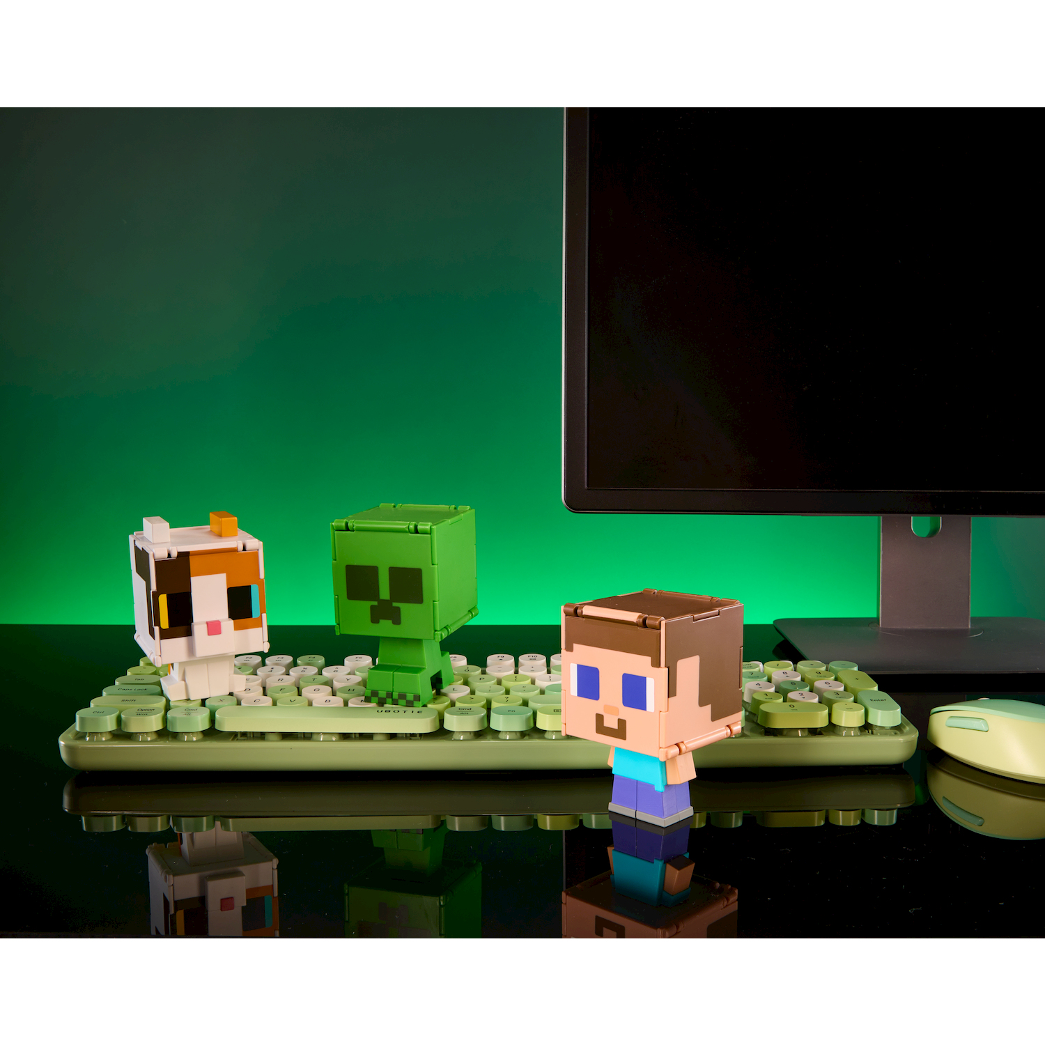 Figure di Minecraft su tastiera verde davanti a un monitor.
