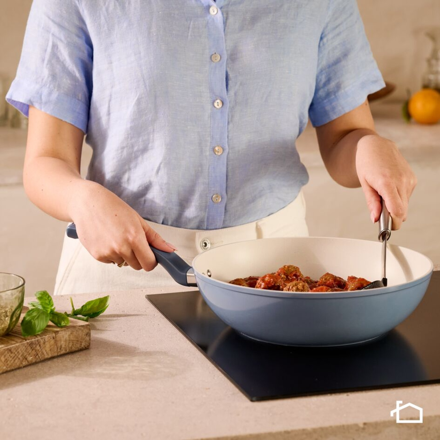 Polpette in salsa di pomodoro sobbollono in una padella blu su un piano cottura a induzione.