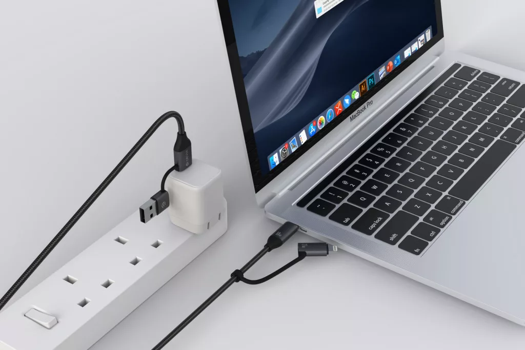 Egy MacBook Pro USB-C kábelen és adapteren keresztül csatlakozik egy elosztóhoz.