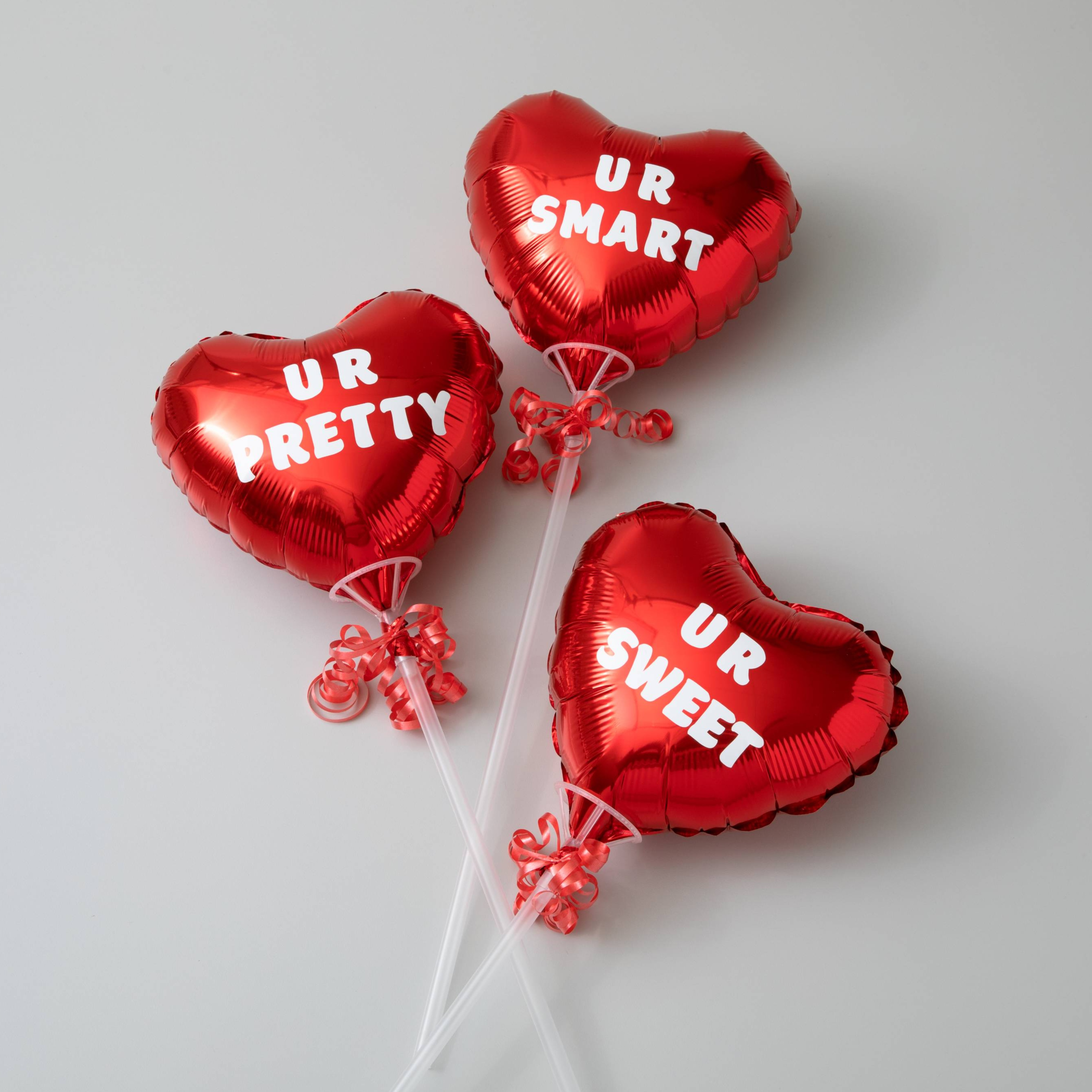 Beyaz yazılı üç kırmızı kalp balon: UR SMART, UR PRETTY, UR SWEET.