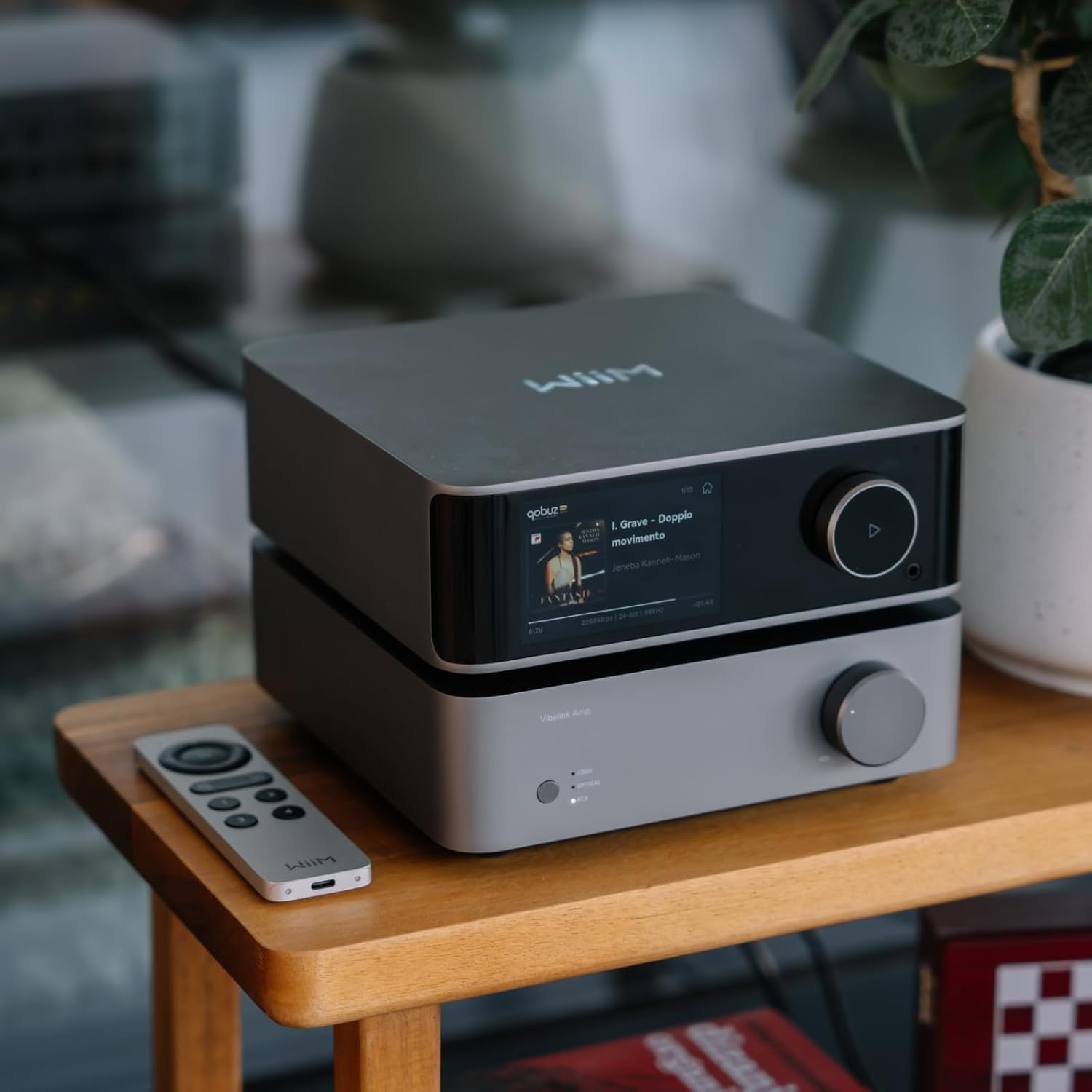 Un lecteur audio et un amplificateur gris sont sur une table en bois. Une télécommande est posée devant.
