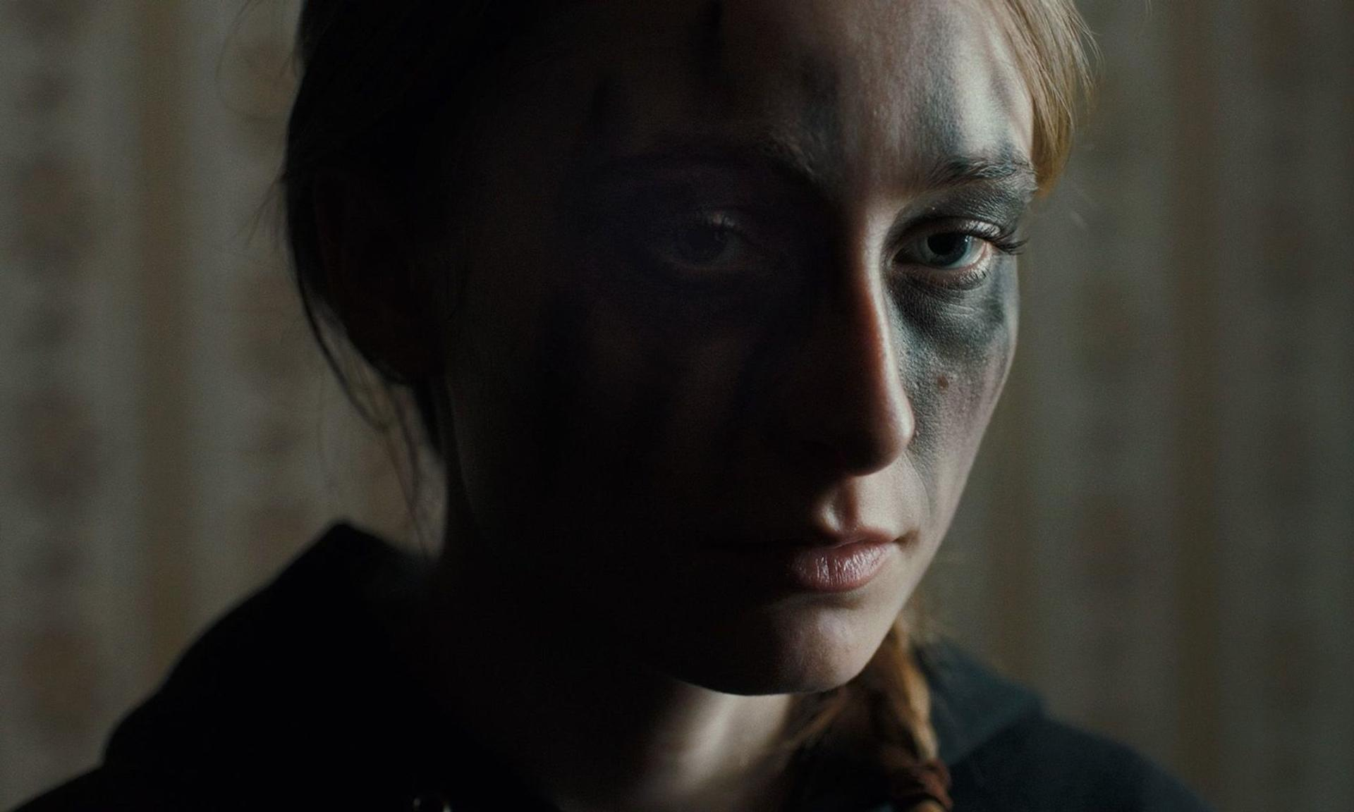 Nahaufnahme einer jungen Frau mit dunklem Make-up um die Augen, im Schatten.