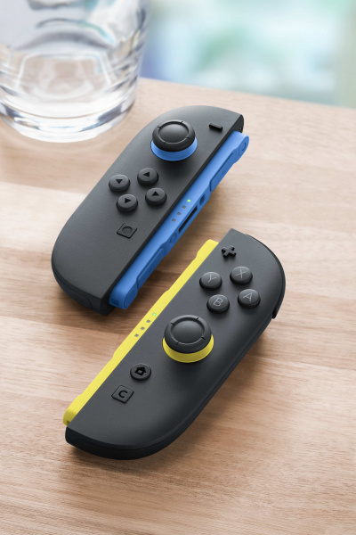 Dwa kontrolery Joy-Con na drewnianym stole, jeden niebieski, jeden żółty.