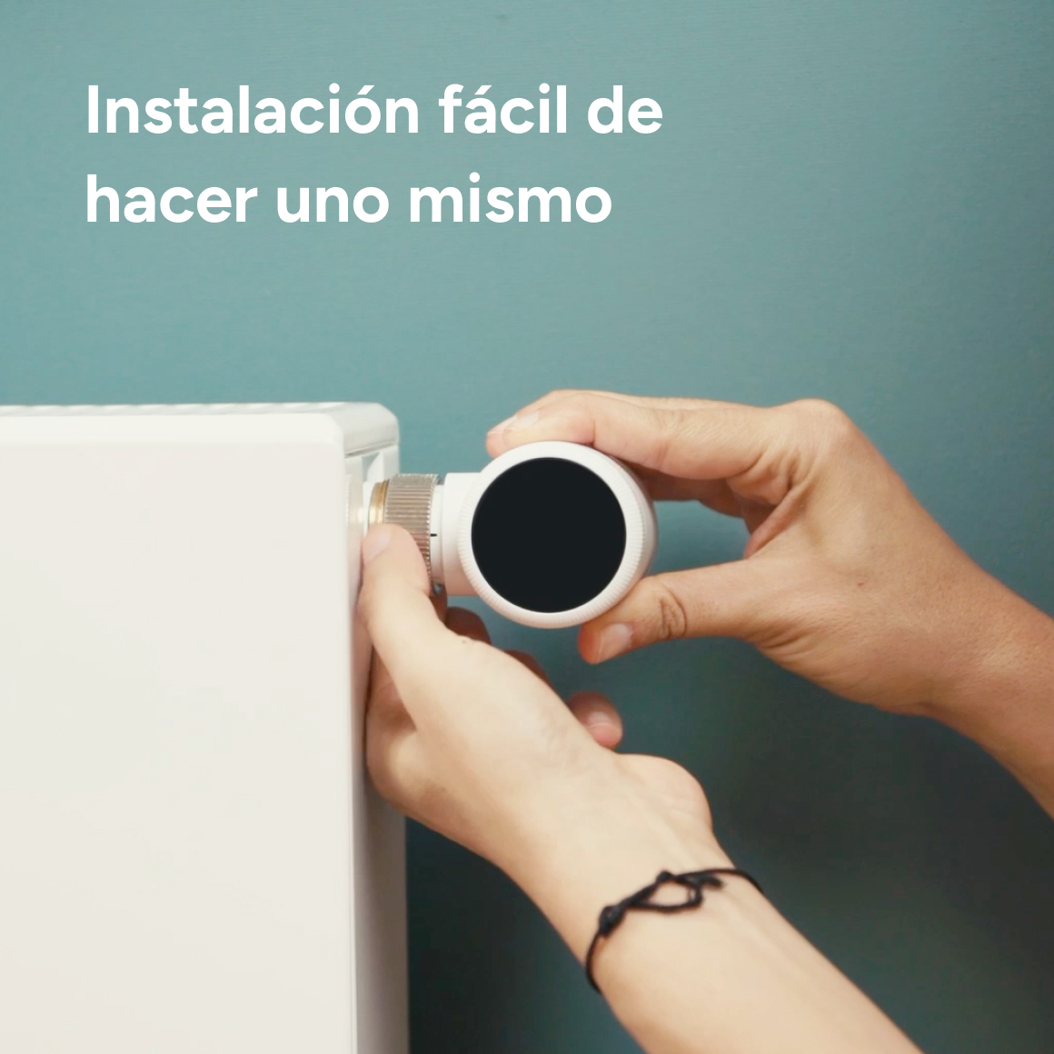 Manos instalando un termostato blanco en un radiador.