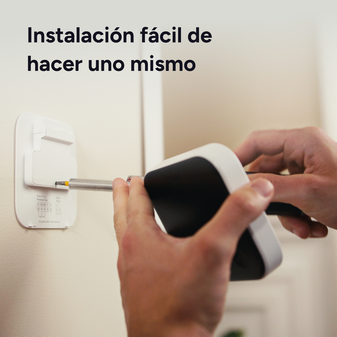Persona instala un dispositivo en una pared con un destornillador.