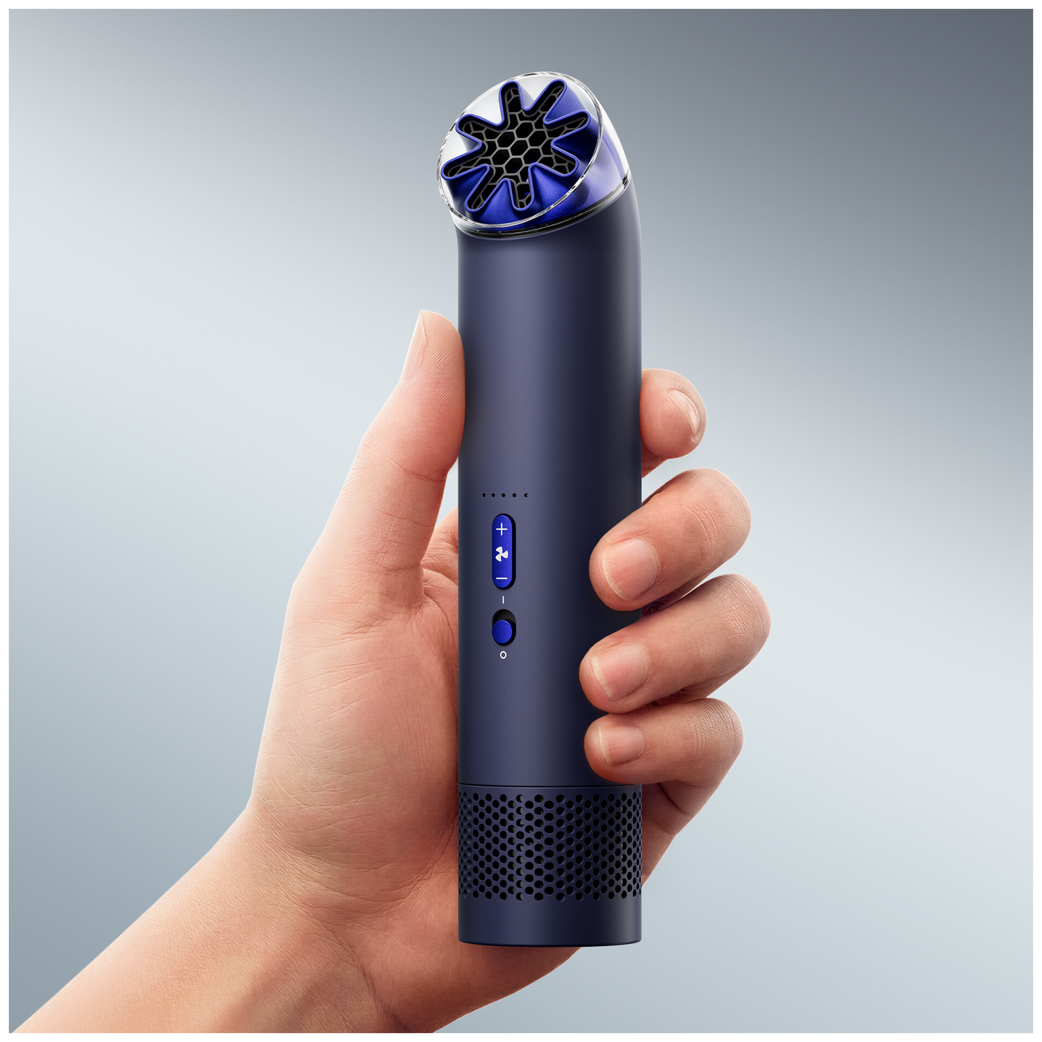 Hand holds a dark blue device with blue accents and a perforated base.