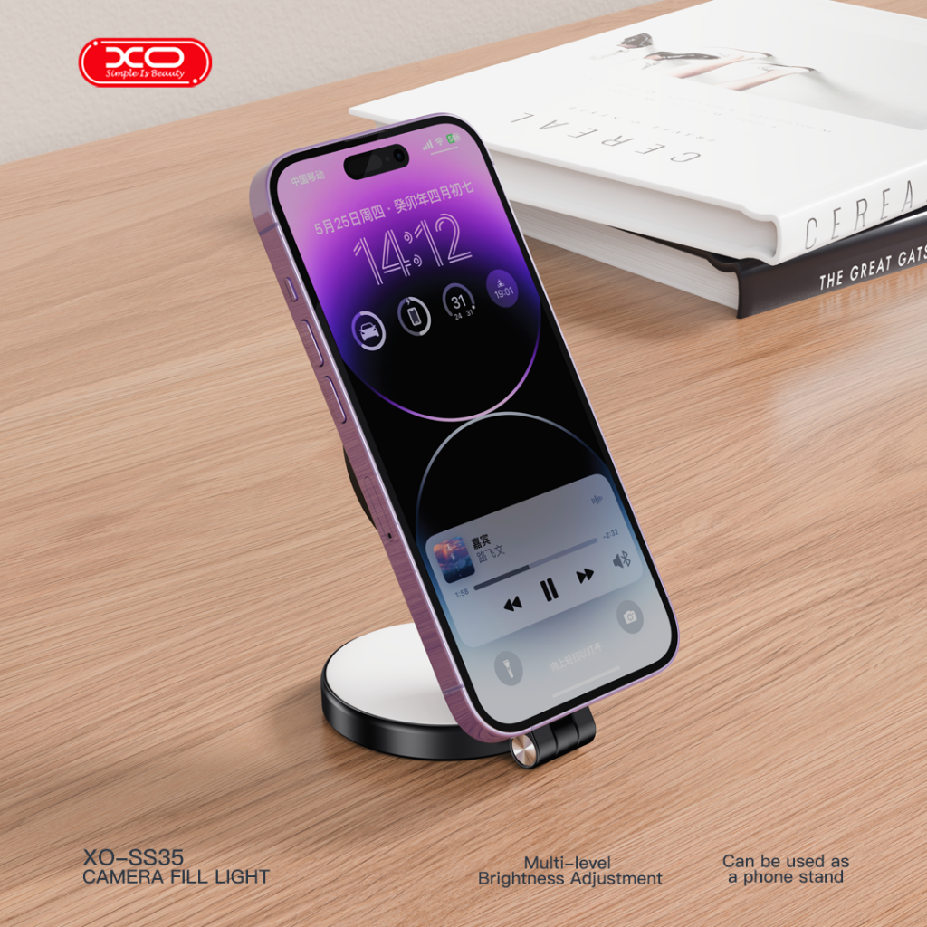 Ahşap bir masada stant üzerinde mor bir telefon, yanında kitaplar.
