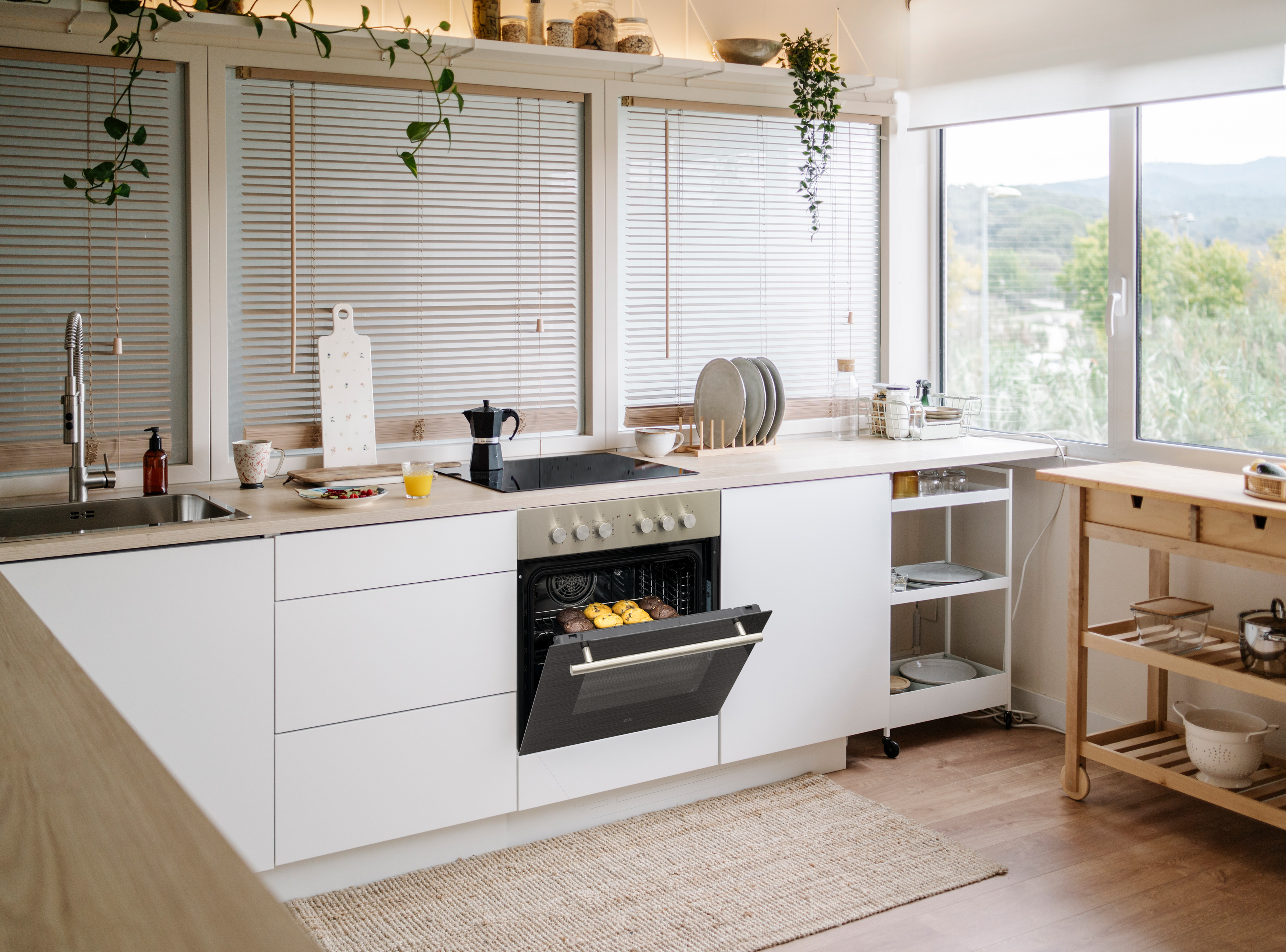 Moderne Küche mit offenen Backofen, in dem Kekse gebacken werden. Draußen ist es grün.