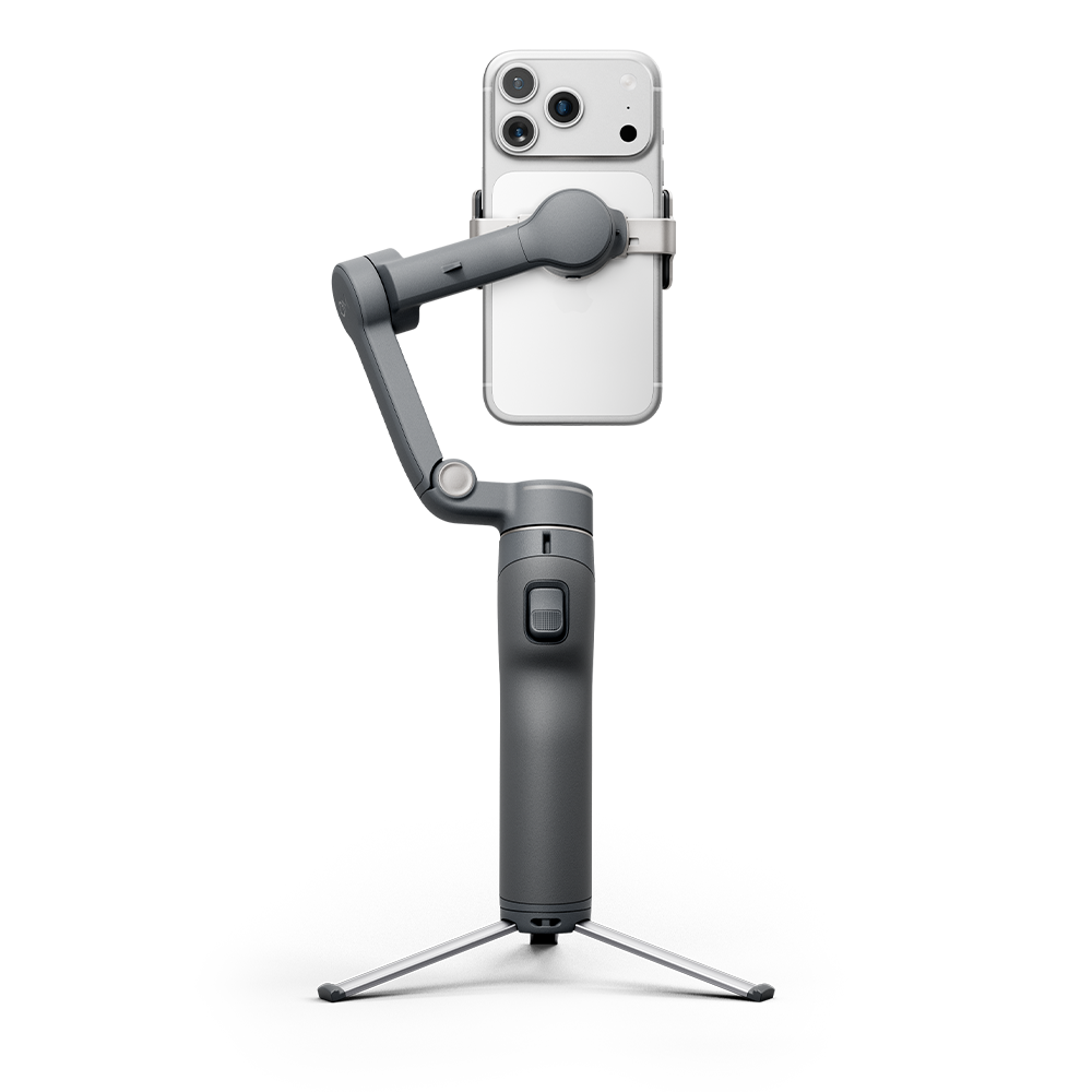 Beyaz akıllı telefonu tutan gri gimbal, küçük bir tripoda monte edilmiş.