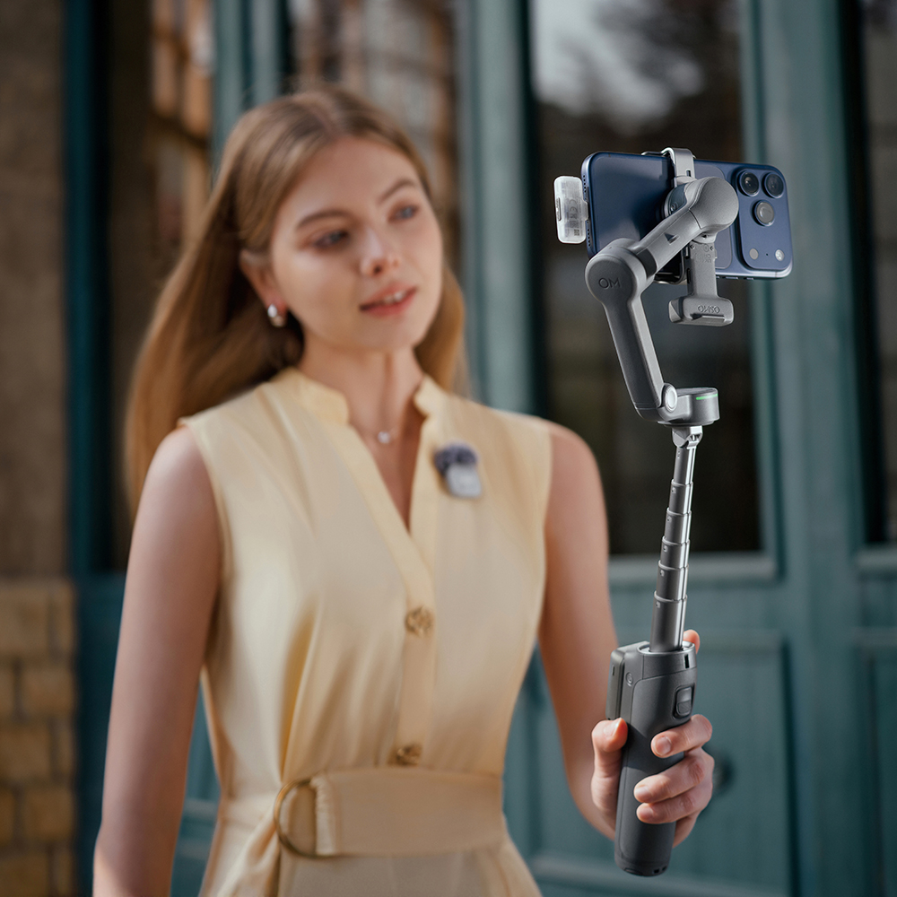 Sarı elbiseli bir kadın akıllı telefonlu gimbal tutuyor.
