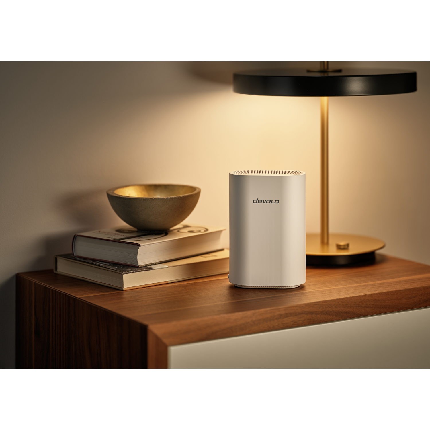 A white router sits on a wooden table next to books and a bowl.