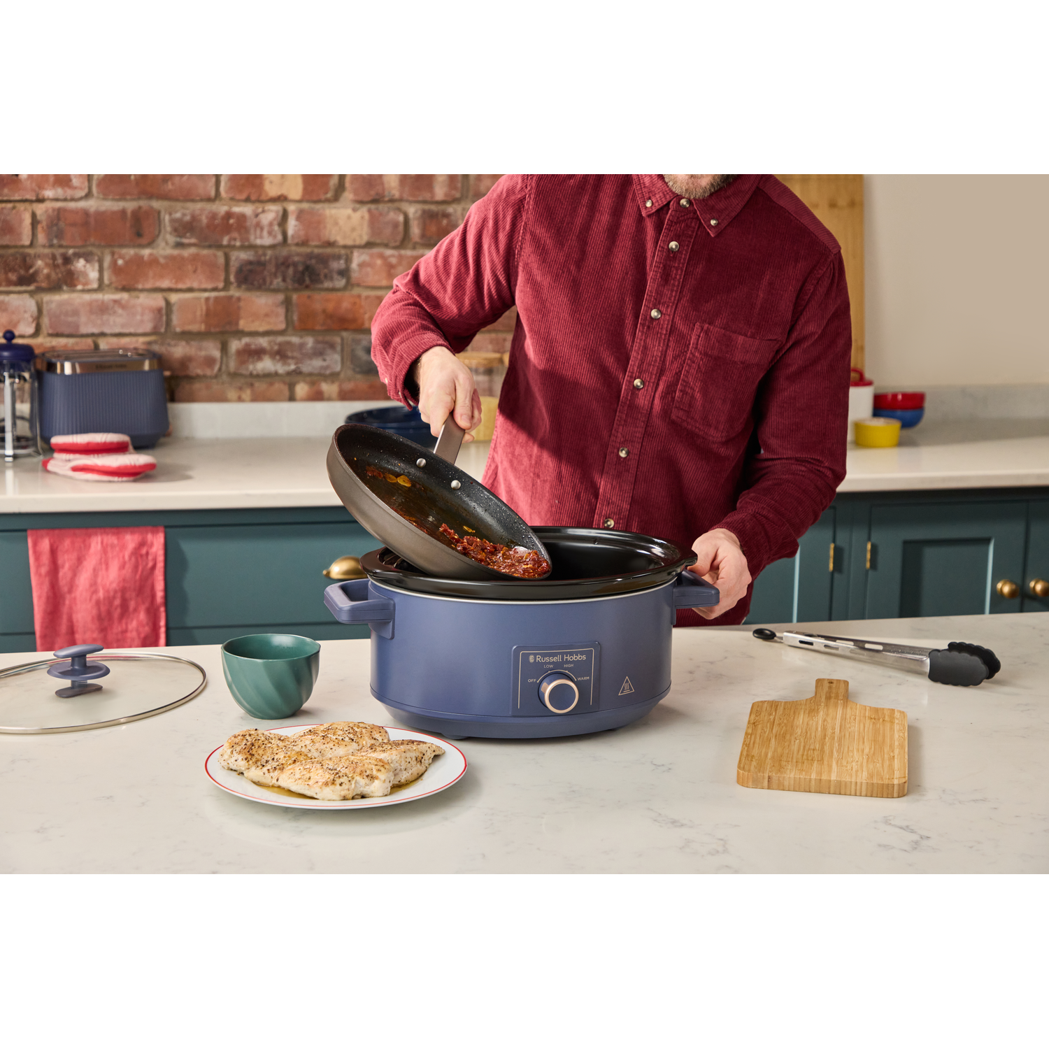 Man giet eten uit pan in blauwe slowcooker. Gekookte kip op bord.