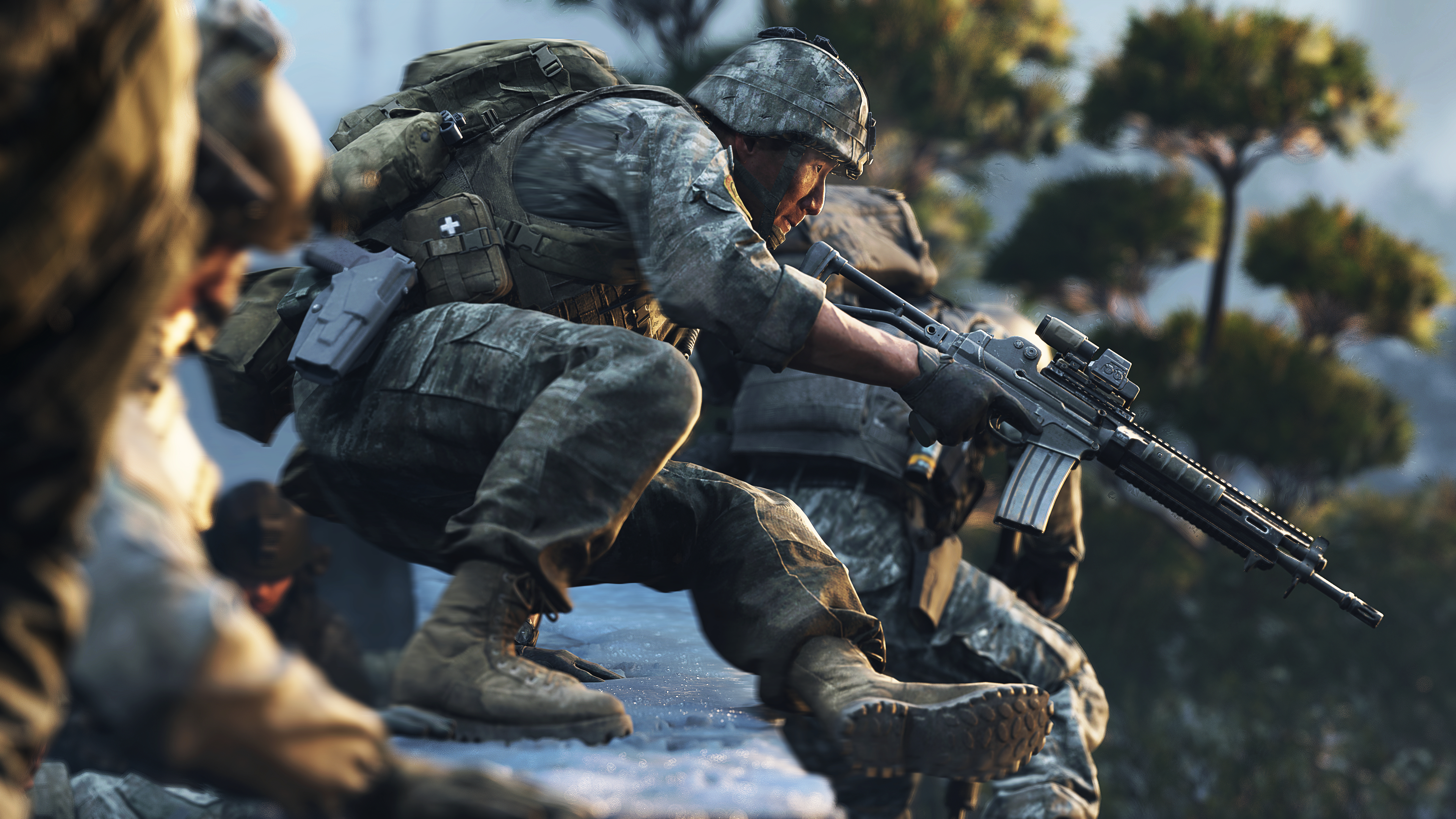 Soldat in Tarnkleidung kauert mit einem Gewehr in der Hand in felsigem Gelände.