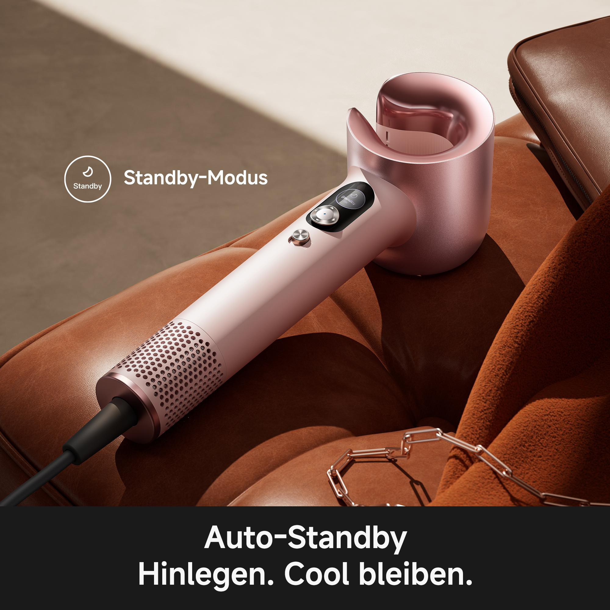 Ein roségoldener Haartrockner liegt auf braunem Leder mit einer Kette.