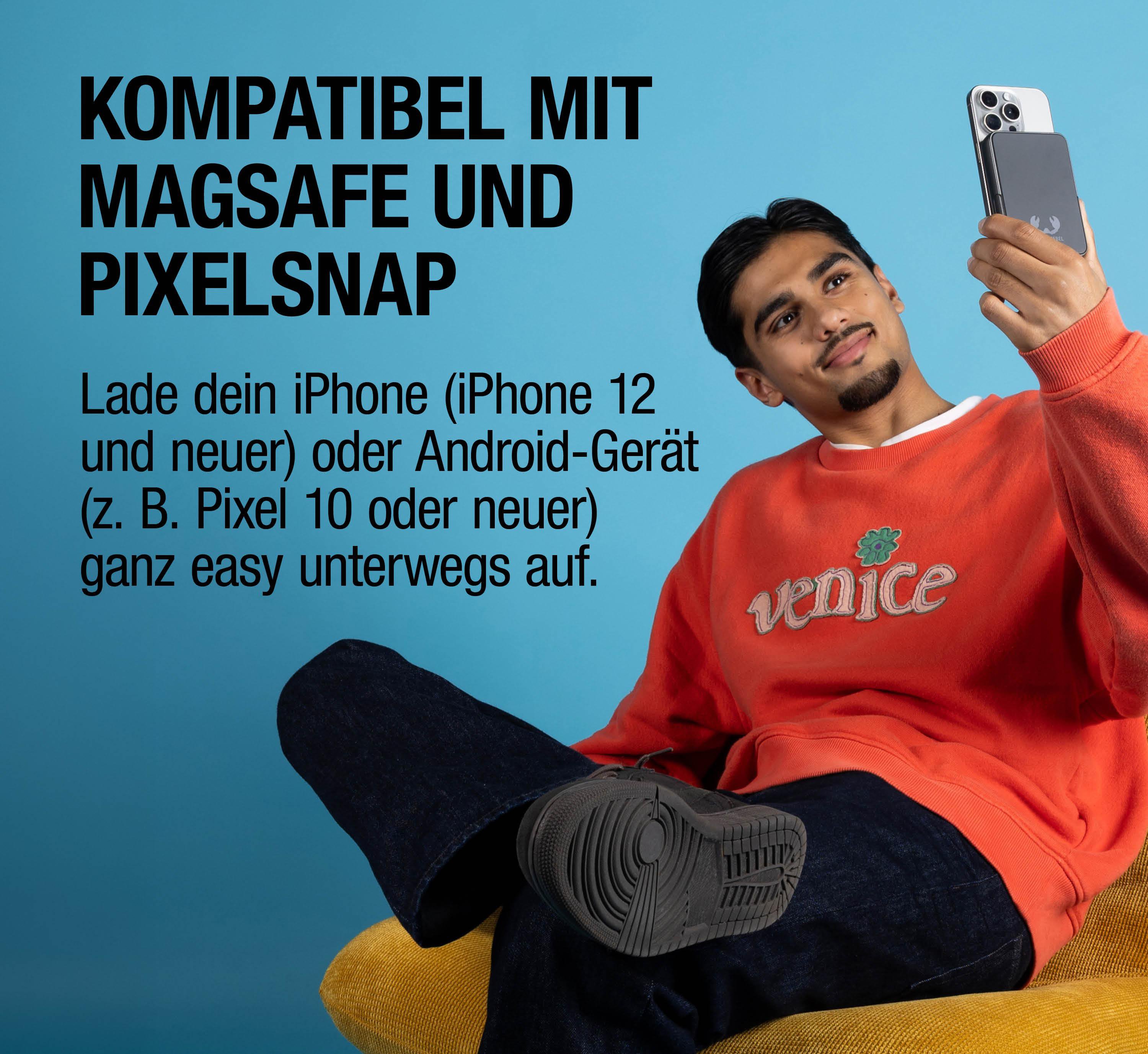 Mann hält Handy mit MagSafe-Ladegerät vor blauem Hintergrund.