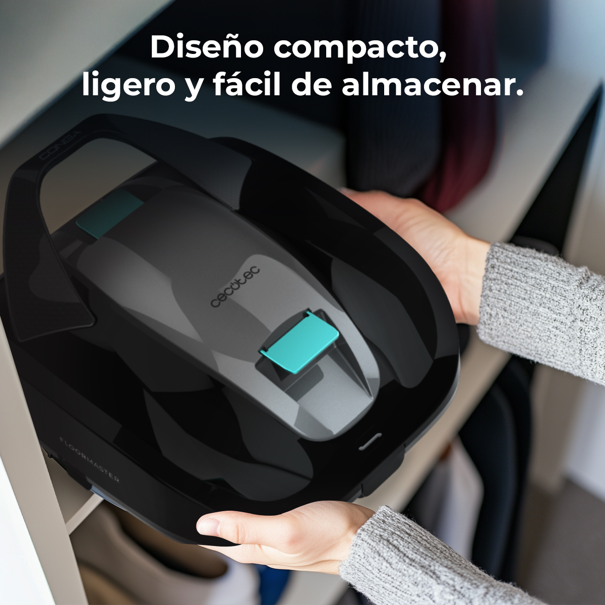 Una mano coloca un robot aspirador negro con detalles turquesa en un estante.