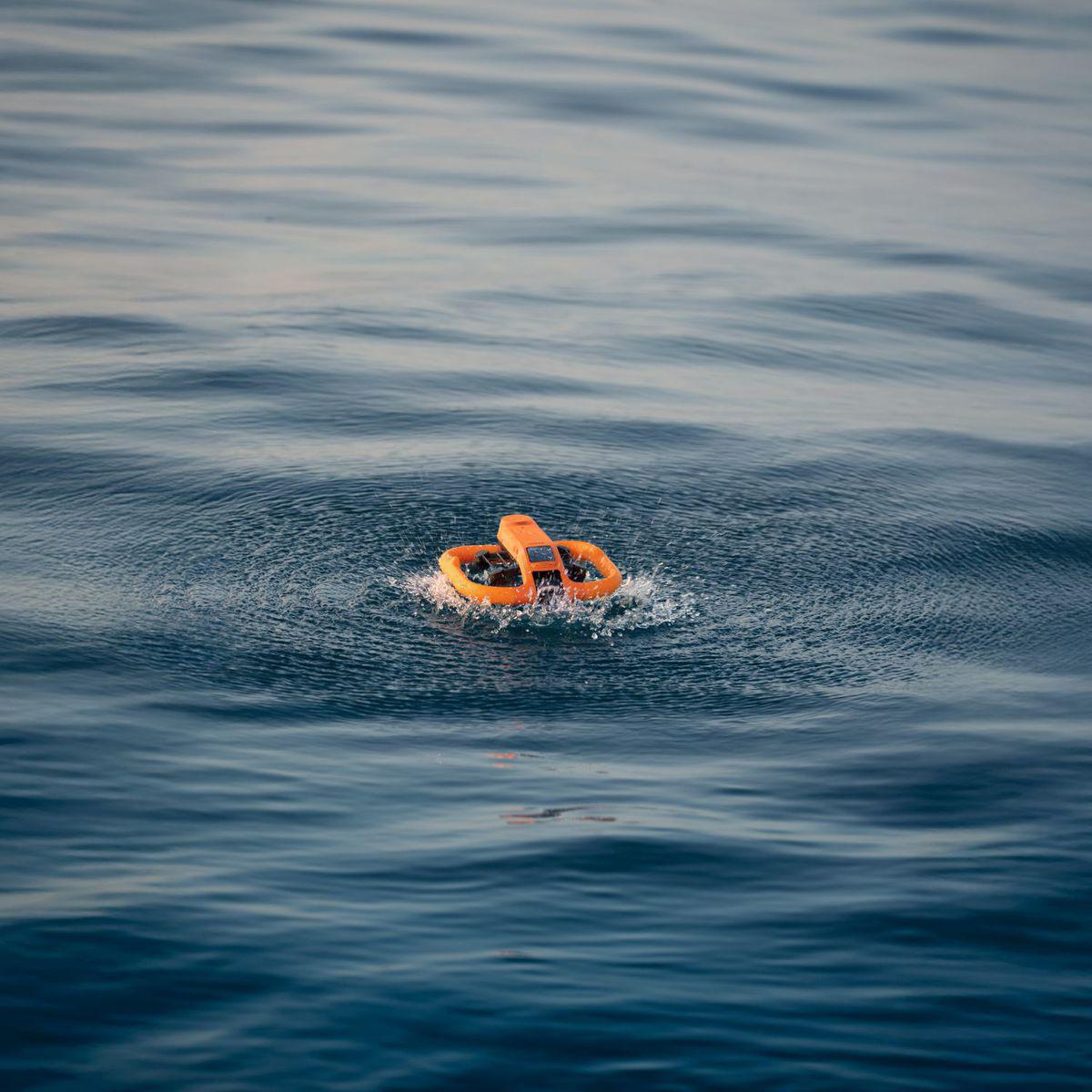 Eine orange Rettungsboje schwimmt in ruhigem blauem Wasser und erzeugt kleine Wellen.