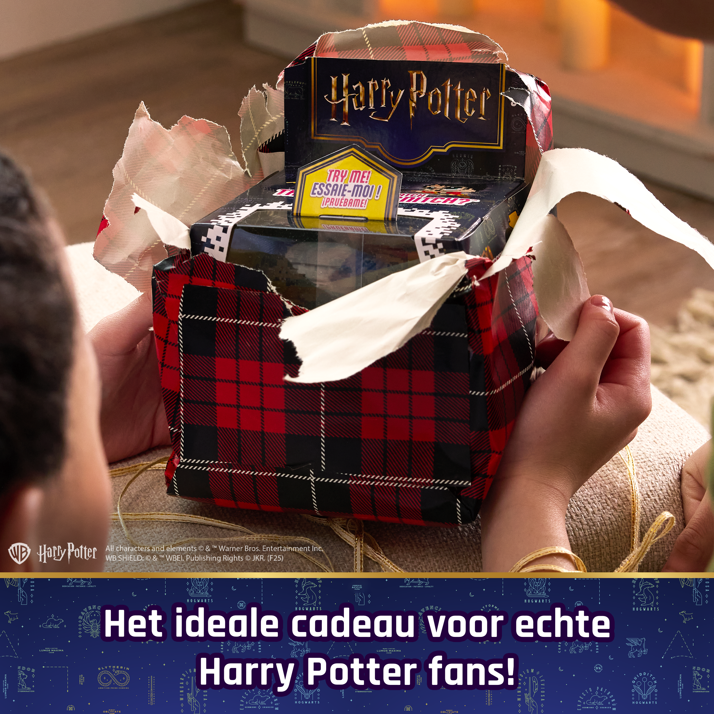 Ktoś rozpakowuje prezent z Harry'ego Pottera, owinięty w czerwono-czarny papier w kratę.