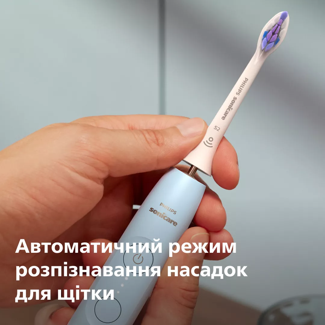 Dłoń trzyma jasnoniebieską szczoteczkę elektryczną z jasnoróżową główką.