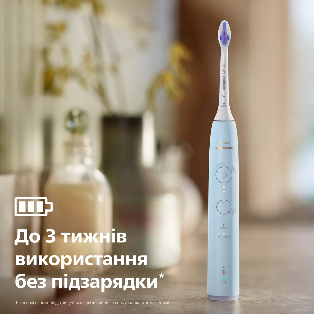 Jasnoniebieska szczoteczka elektryczna z dwiema butelkami w tle.