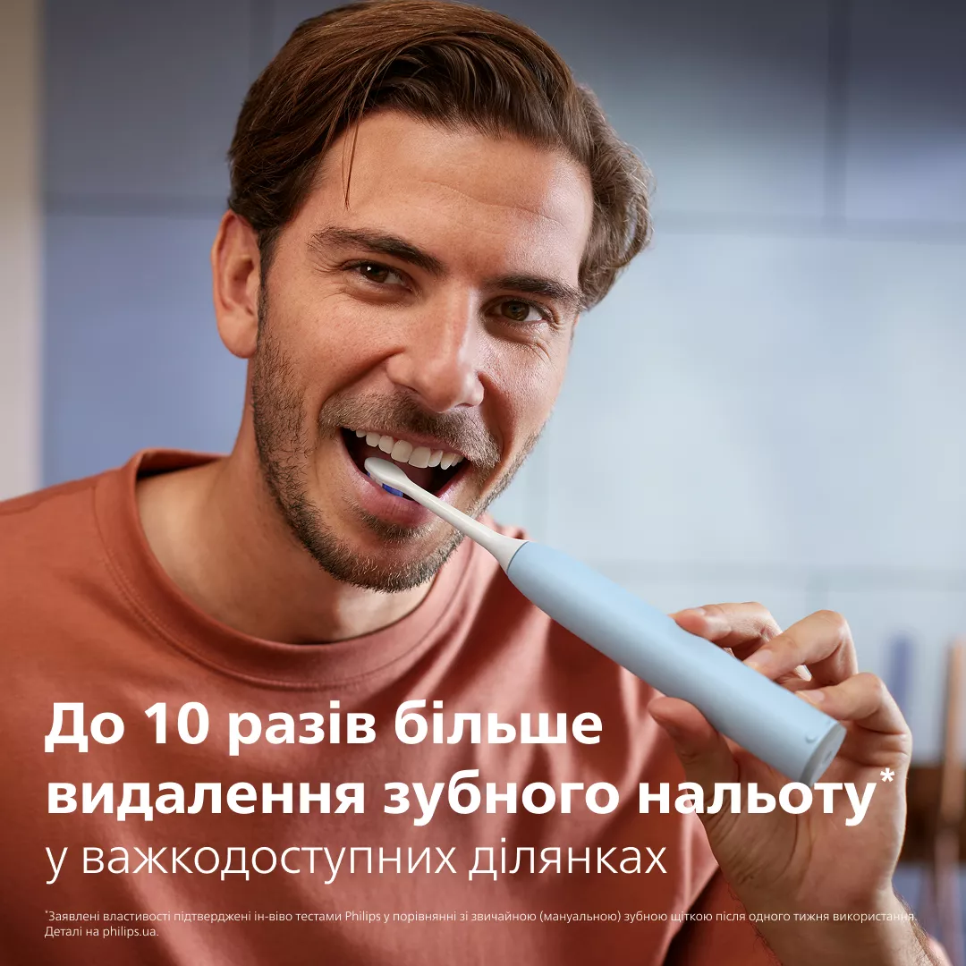 Mężczyzna myje zęby jasnoniebieską szczoteczką elektryczną. Zbliżenie.
