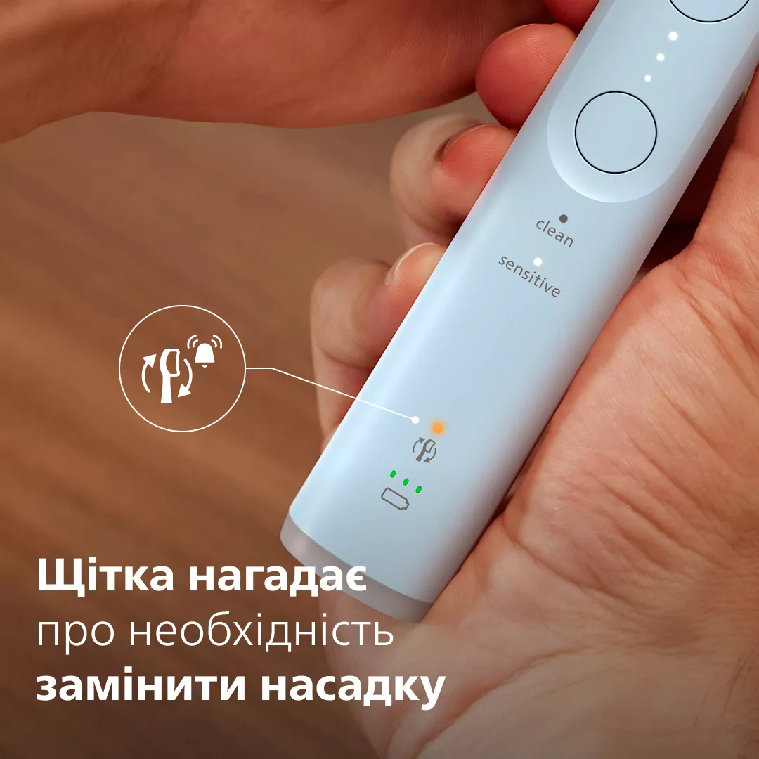Jasna rączka szczoteczki elektrycznej z pomarańczowym światłem ostrzegawczym i ikonami.