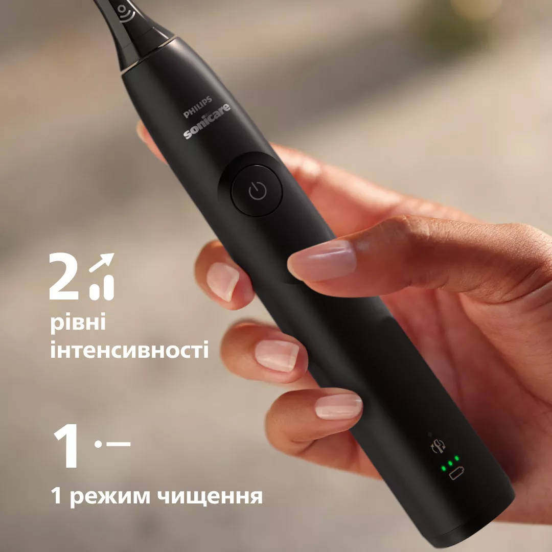 Dłoń trzyma czarną szczoteczkę elektryczną ze światłami i tekstem.
