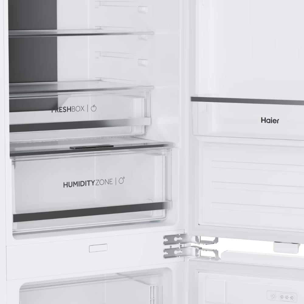 Innenraum eines weißen Haier-Kühlschranks mit Regalen, einer Freshbox und einer Humidity Zone Schublade.