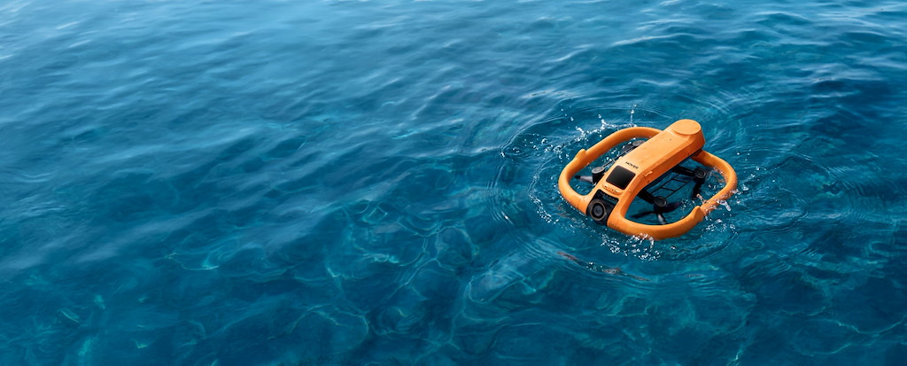 Ein orangefarbener Unterwasser-RC-Quadrocopter treibt auf dem blauen Wasser.