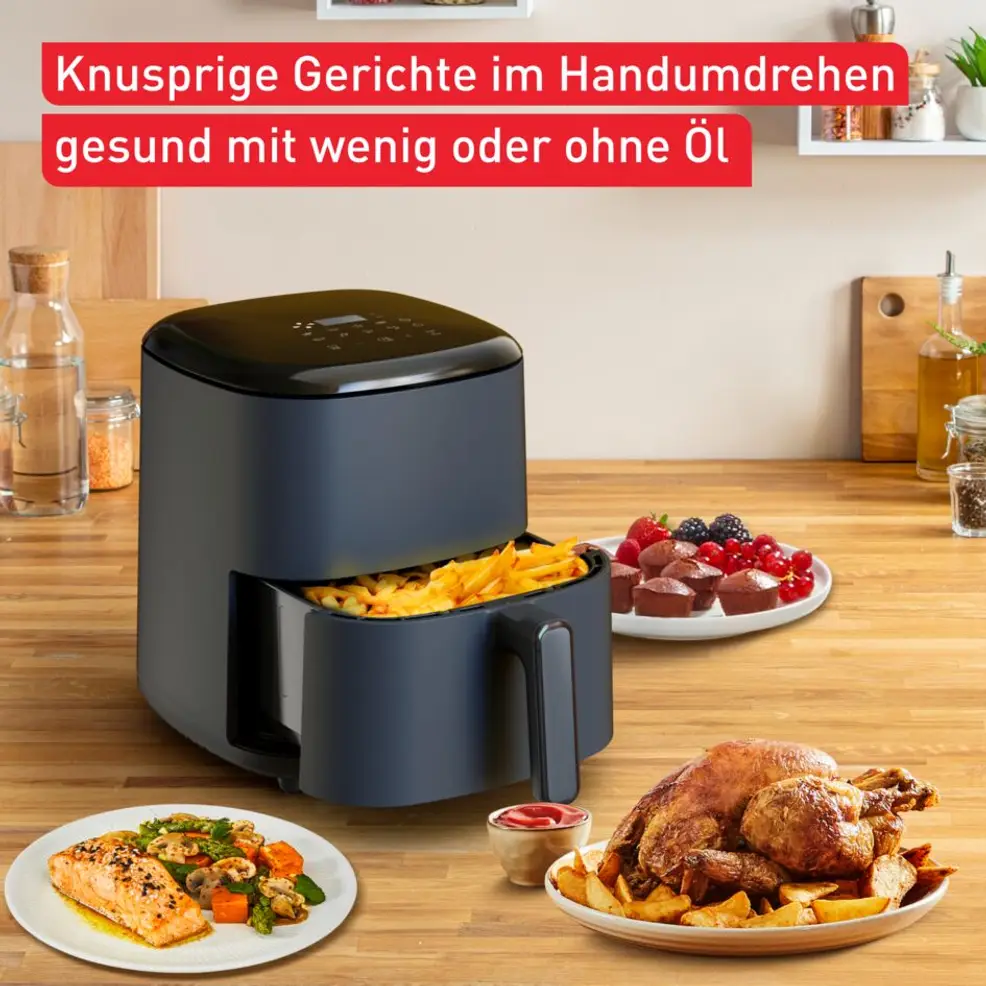 Frigitteuse à air gris foncé avec frites, à côté poulet rôti, saumon et desserts.