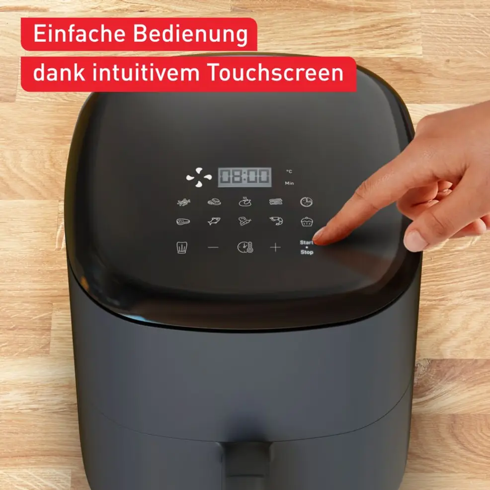 Une main appuie sur le bouton de démarrage d'une friteuse à air noire avec écran tactile.