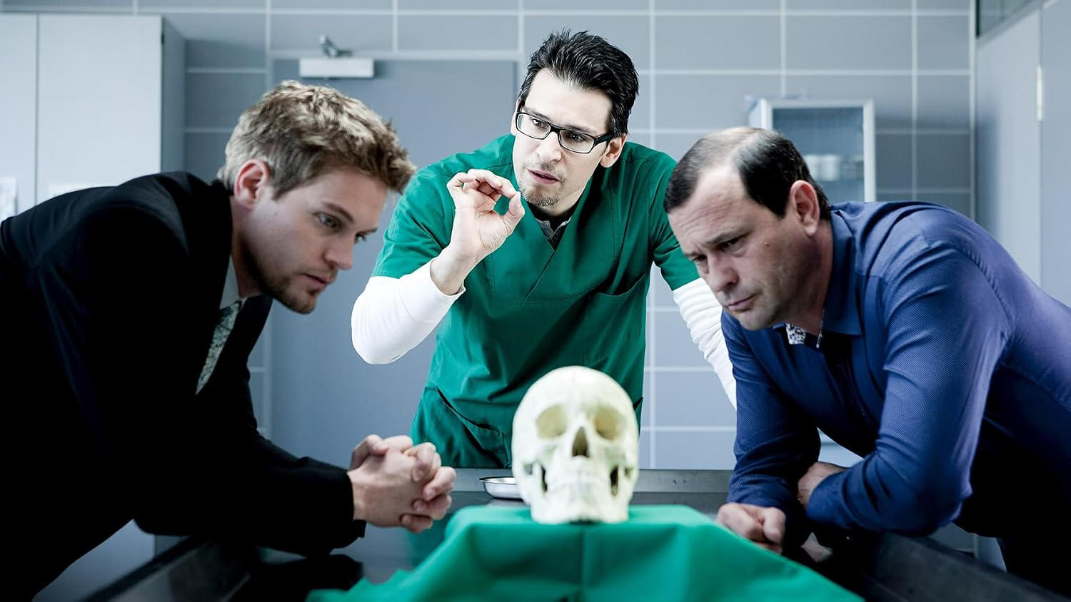 Drei Männer betrachten einen Schädel auf einem Tisch in einem Labor.