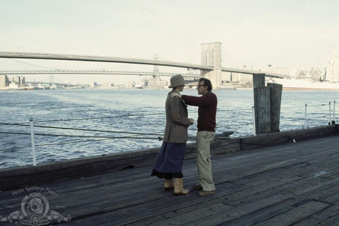 Mann und Frau auf Pier, Brooklyn Bridge und Stadtbild im Hintergrund.