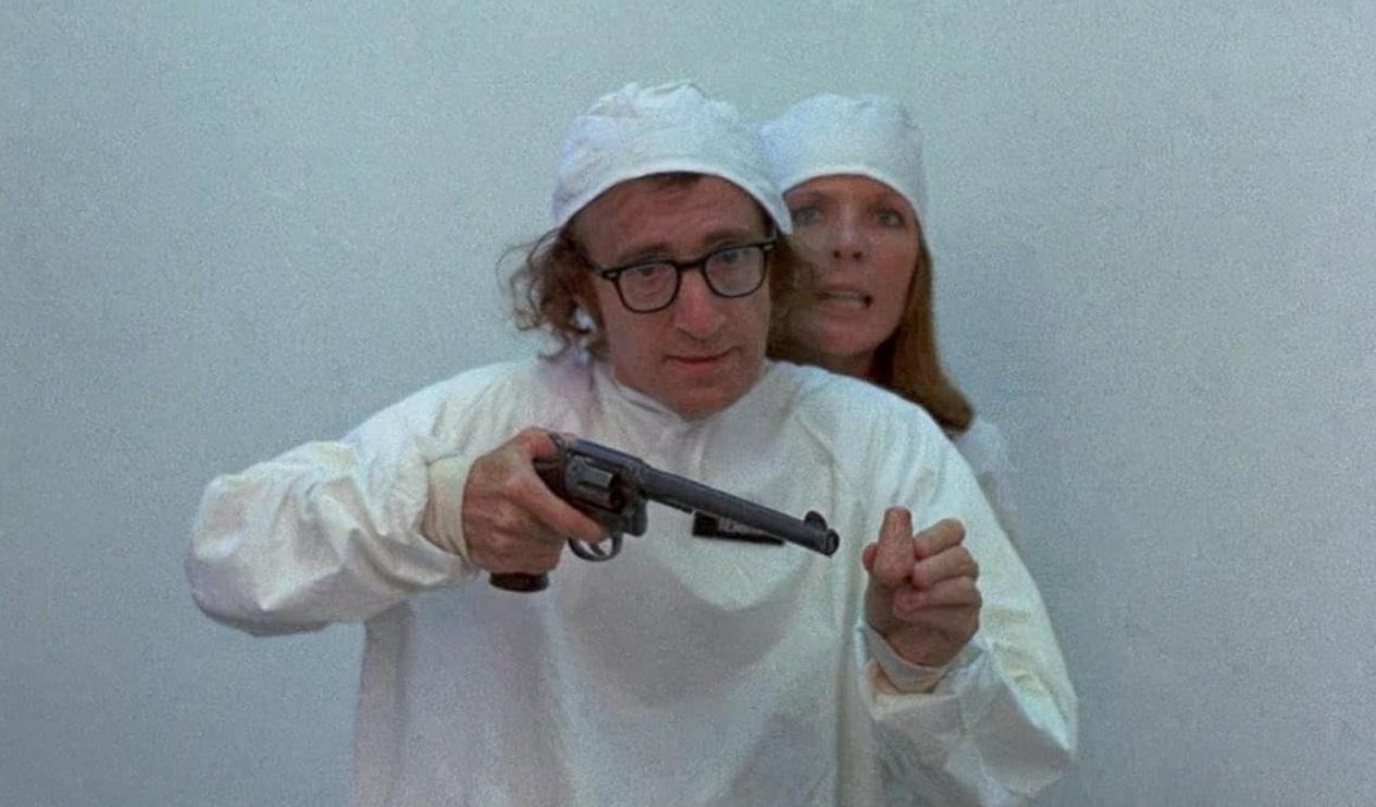 Mann mit Brille und Frau in weißen Kitteln, Mann hält Revolver.