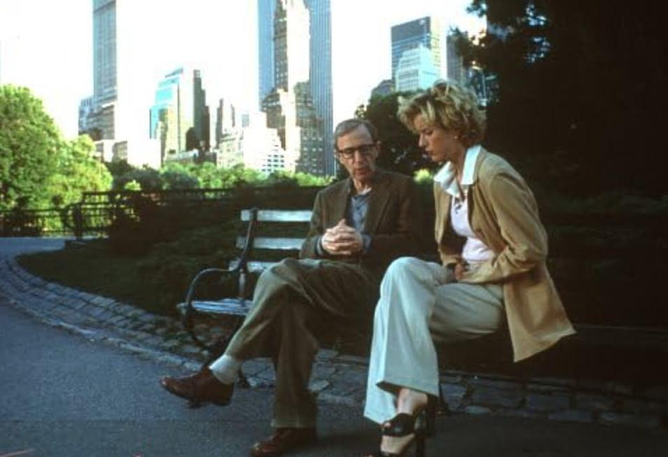 Mann und Frau sitzen auf einer Parkbank mit Wolkenkratzern im Hintergrund.