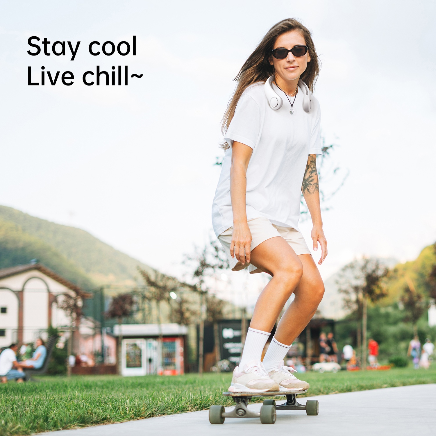 Femme faisant du skateboard en extérieur, portant des vêtements blancs et des lunettes de soleil.